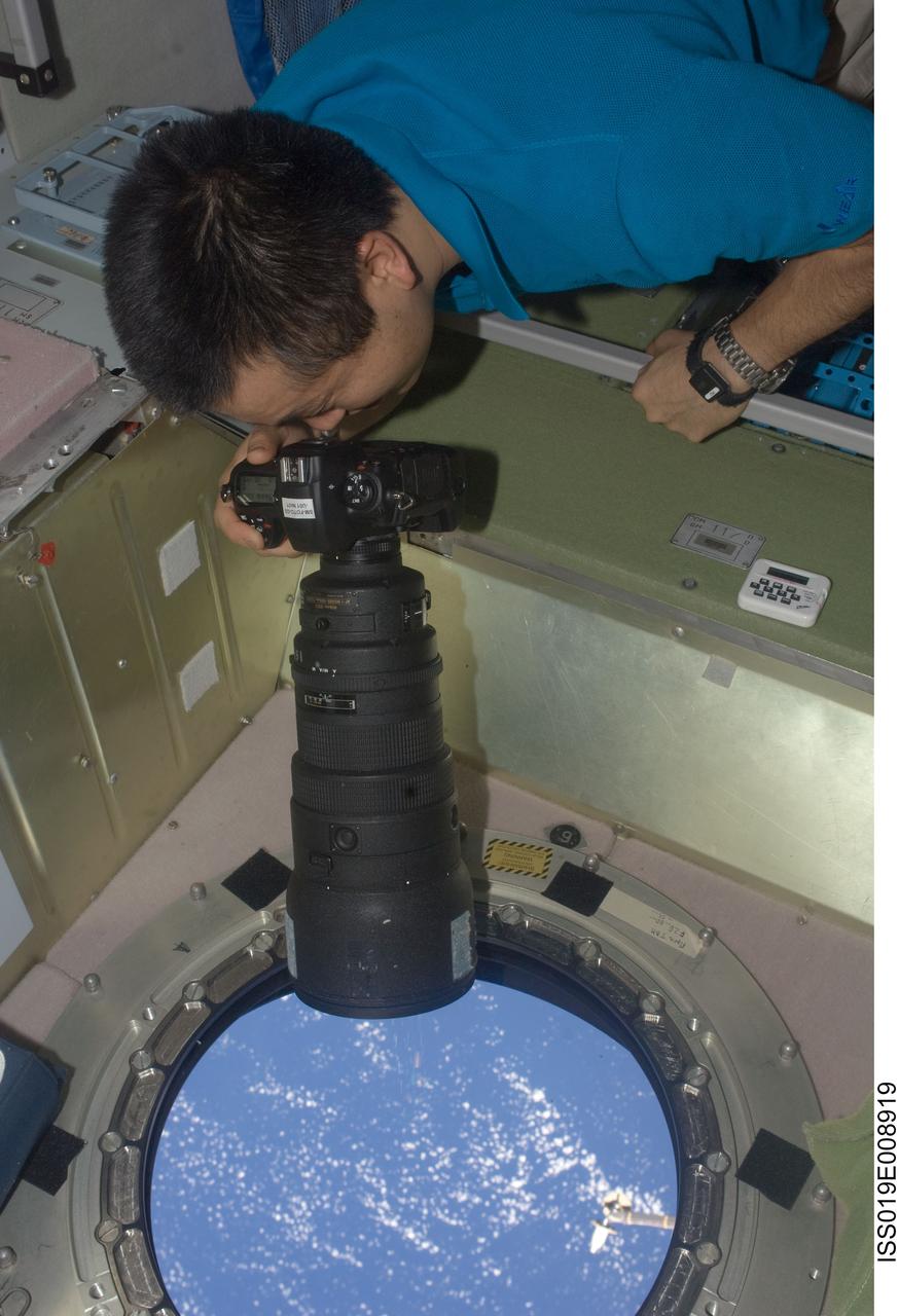 ISS019-E-008919 (19 April 2009) --- Japan Aerospace Exploration Agency (JAXA) astronaut Koichi Wakata, Expedition 19/20 flight engineer, uses a still camera at a window in the Zvezda Service Module of the International Space Station.