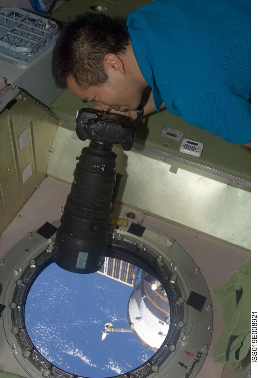 ISS019-E-008921 (19 April 2009) --- Japan Aerospace Exploration Agency (JAXA) astronaut Koichi Wakata, Expedition 19/20 flight engineer, uses a still camera at a window in the Zvezda Service Module of the International Space Station.