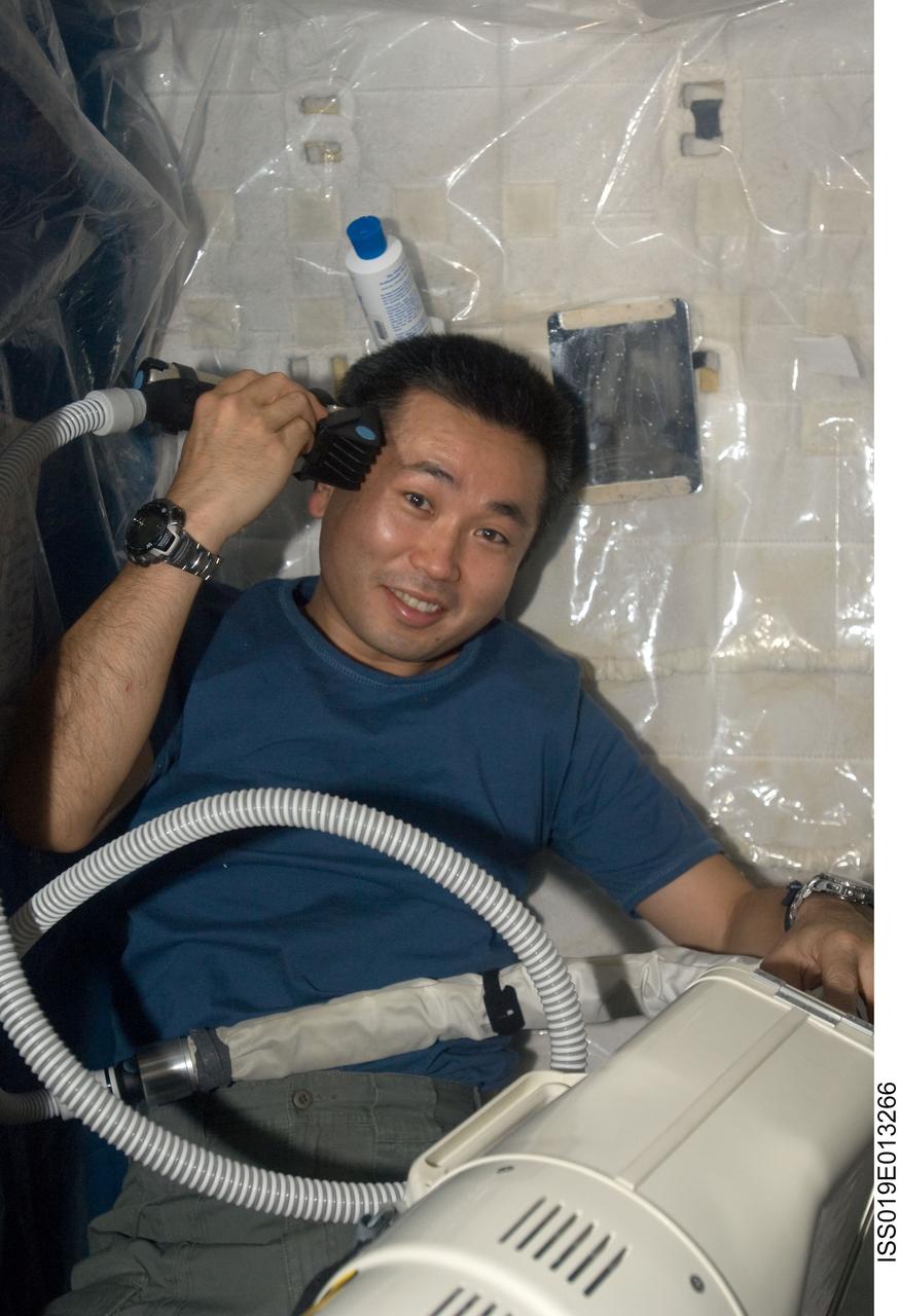 ISS019-E-013266 (3 May 2009) --- Japan Aerospace Exploration Agency (JAXA) astronaut Koichi Wakata, Expedition 19/20 flight engineer, trims his hair in a crew compartment on the International Space Station, using hair clippers fashioned with a vacuum device to garner freshly cut hair.