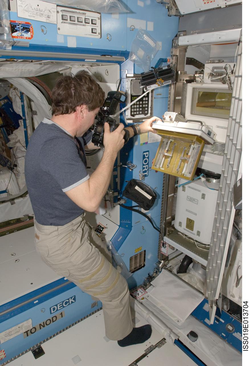 ISS019-E-013704 (4 May 2009) --- Astronaut Michael Barratt, Expedition 19/20 flight engineer, uses a still camera in the Destiny laboratory of the International Space Station.