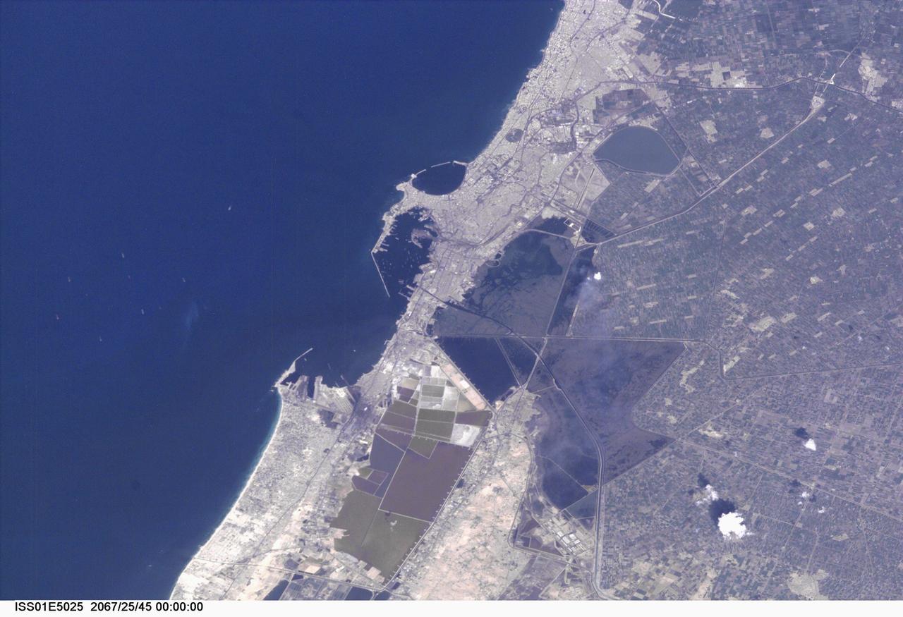 ISS01-E-5025 (November 2000) --- This nadir view of Alexandria, Egypt, was provided by a digital still camera image down linked from the International Space Station to flight controllers in Houston. Alexandria (Al Iskandariya) occupies a T-shaped peninsula and strip of land separating the Mediterranean from Lake Mariout. According to NASA scientists studying the Expedition One photo collection, the town was originally built upon a mole (stone breakwater) called Heptastadium, which joined the island of Pharos to the mainland. Since then, the scientists say, sedimentary deposits have added considerably to the width of the mole.    Since 1905, when the city&#0146;s 370 thousand inhabitants lived in an area of about four square kilometers between the two harbors, the city (population 4 million) has grown beyond its medieval walls and now occupies an area of about 300 square kilometers. The Mahmudiya Canal, connecting Alexandria with the Nile, runs to the south of the city and, by a series of locks, enters the harbor of the principal port of Egypt (note ships). The reddish and ochre polygons west of Lake Mariout are salt-evaporation, chemical-storage, and water-treatment ponds within the coastal lagoon.