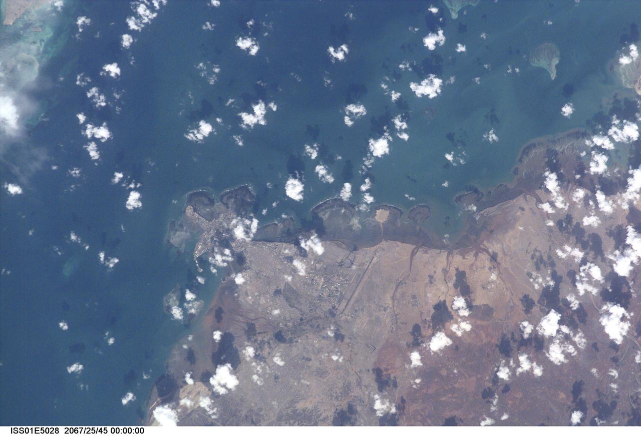 ISS001-E-5028 (December 2000) --- Djibouti, the capital city of the country of Djibouti, can be seen in this northeast-looking view taken from the International Space Station (ISS) with a digital still camera using a 400mm lens. Djibouti, scarcely 100 years old, sits on the western shore of an isthmus in the Gulf of Tadjoura, an arm of the Gulf of Aden. Djibouti is surrounded by a rugged and bleak landscape, that has a dry and hot climate. The population of Djibouti has grown from an estimated 96,000 in 1973 to over 330,000 in 1991 mainly due to the influx of refugees from the neighboring, war torn countries of Ethiopia and Somalia. With its strategically located port, Djibouti’s economic importance results from the large transit trade it enjoys as the terminus of a railroad line from Addis Ababa in Ethiopia. The city has seen an increase in tourism in the past decade due a large number of cruise ships visiting the port. Besides tourism, salt production and shipbuilding and repair are other major industries. Below the center of the image, the long runway of the Djibouti/Ambouli International Airport is visible. Coral reefs are discernible in the upper left and upper right quadrants of the image.