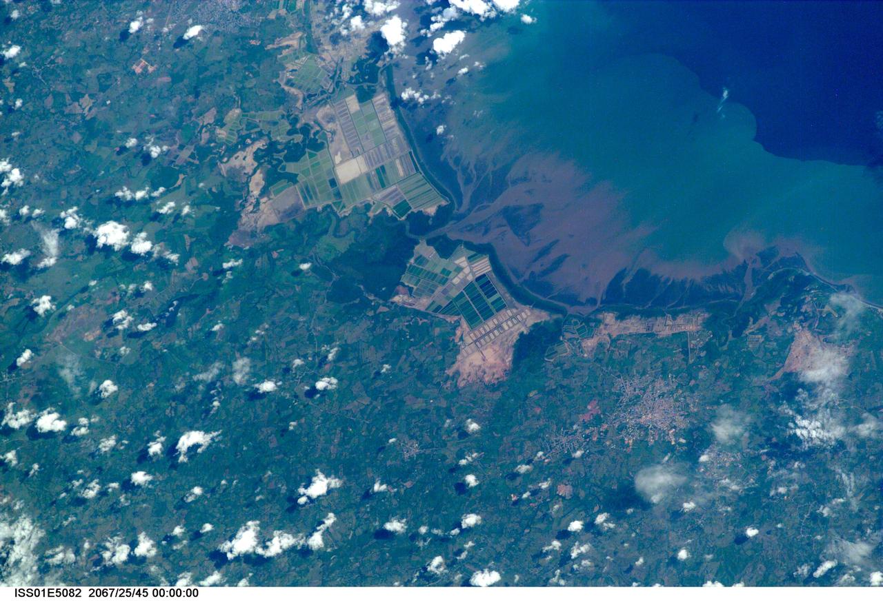 ISS01-E-5082 (December 2000) ---   This image of coastal Asia was taken from the International Space Station with a digital still camera and a 400mm lens with a very narrow field of view.  Early in the Space Station Program, communications with the crew are less direct, and the exact time that this image was taken could not be determined.  Because there are relatively few photograph of Earth taken with this long lens, and because the times are not available to calculate the exact position of the Station over the Earth when the photograph was taken, the exact location of the photograph cannot be determined.  Many of these logistical problems will be resolved as camera equipment is replaced and communications with the crew improve.  Catalogers believe the coast most resembles Indonesia, and this determination will be maintained until future images allow correction and refinement of the location.  The photograph is a striking example of the degree to which humans modify coastal environments.  The large green squares in the image probably represent a combination of rice cultivation and aquaculture.