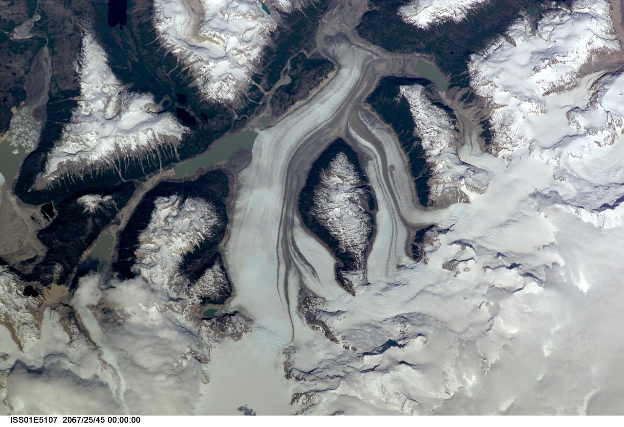 ISS01-E-5107 (December 2000) --- This nadir view of a Chilean glaciated area was provided by one of the early December digital still camera images down linked from the International Space Station (ISS) to ground controllers in Houston. The remote headwaters of the Rio de la Colonia are located on the eastern flank of the Cerro Pared Norte, a high, coastal range of the Andes in southern Chile. This is but a portion of a larger glaciated region of the Chilean coast located at only 47 degrees south latitude. The river actually begins its flow just off the top of this scene at the foot of the two large, converging, valley glaciers near the center. Some of the numerous lakes visible are tinted by the fine glacial sediments suspended in their waters. Note the shards of ice that have calved from the glaciers into the lakes on the left. Also note the shadows of the crest of the over 14,000-foot mountains (lower center). The remote headwaters of the Rio de la Colonia are located on the eastern flank of the Cerro Pared Norte, a high, coastal range of the Andes in southern Chile. This is a but a portion of a larger glaciated region of the Chilean coast located at only 47 degrees south latitude. The river actually begins its flow just off the top of this scene at the foot of the two large, converging, valley glaciers near the center. Some of the numerous lakes visible are tinted by the fine glacial sediments suspended in their waters. Note the shards of ice that have calved from the glaciers into the lakes on the left. Also note the shadows of the crest of the over 14,000-foot mountains (lower center).