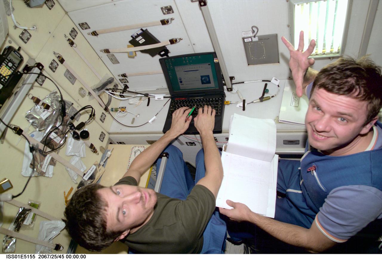 ISS01-E-5155 (December 2000) --- Cosmonauts Sergei K. Krikalev (left),  Expedition One flight engineer, and   Yuri P. Gidzenko, Soyuz commander,  input data into a laptop computer in the Zvezda Service Module aboard the Earth-orbiting International Space Station (ISS).