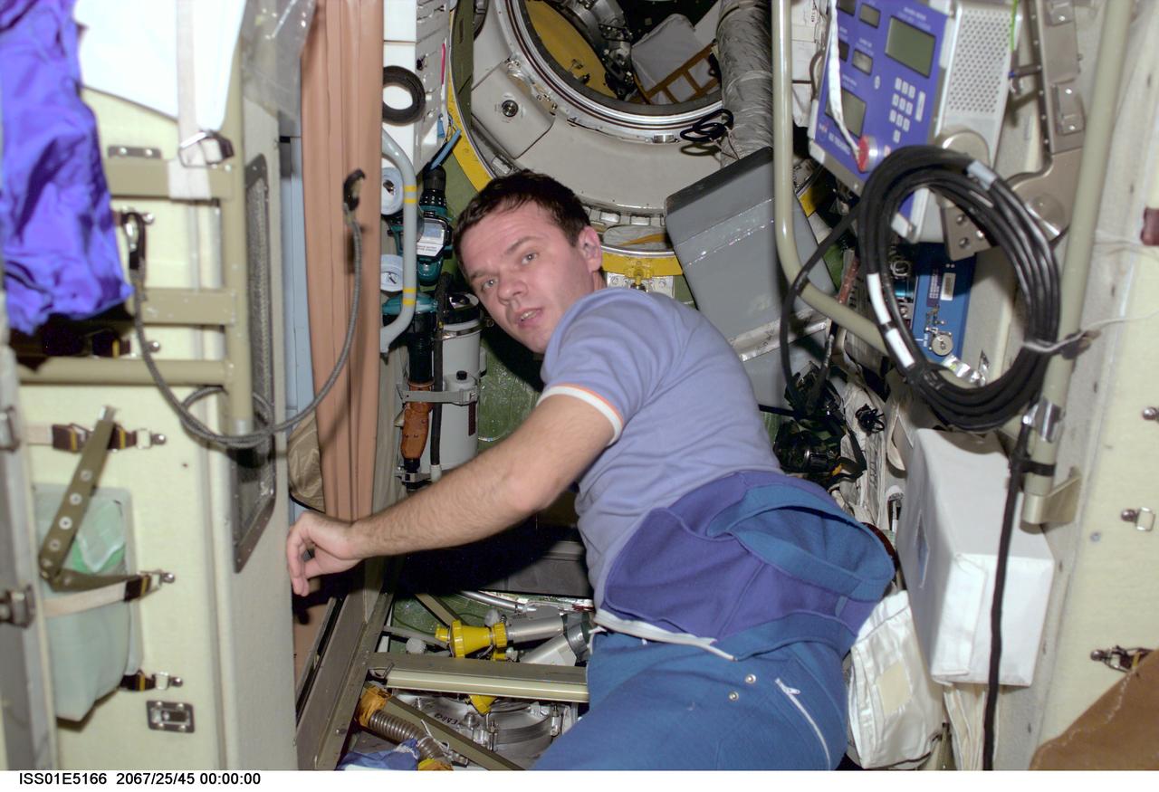 ISS01-E-5166 (December 2000) --- Cosmonaut Yuri P. Gidzenko, Soyuz commander for Expedition One, performs some electrician's work just outside the   waste management compartment in the  Zvezda Service Module of the Earth-orbiting International Space Station (ISS).