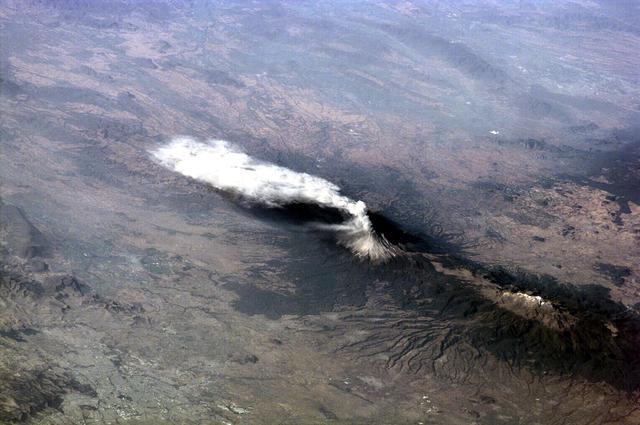 ISS01-E-5316 (23 January 2001) -- Popocat&#0233;petl, or Popo, the active volcano located about 70 kilometers southeast of Mexico City, sends a plume south on January 23, 2001.  The Expedition One crew onboard the International Space Station (ISS) observed and recorded this image with a digital still camera as it orbited to the northeast of the volcano. Popo has been frequently active for six years.  On this day, the eruption plume reportedly rose to more than 9 kilometers above sea level  (for reference, Popo's summit elevation is 5426 meters).  Note the smaller ash plume below the main plume.  The perspective from the ISS allowed the crew members this unique three dimensional view. Popo is situated between two large population centers:  Mexico City (more than 18 million people, and just out of this image at right) and Puebla (about 1.2 million people), partially visible at lower left.