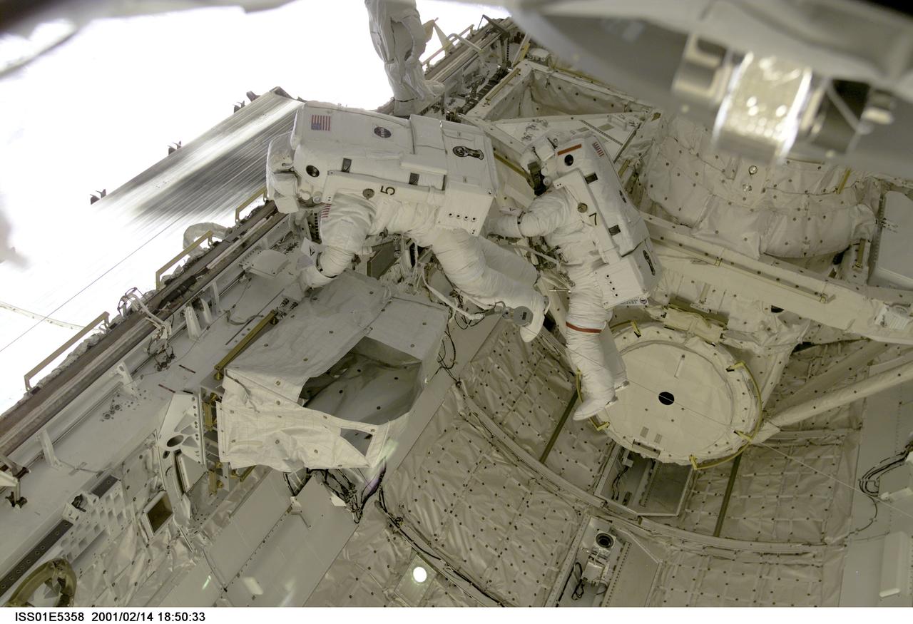 ISS01-E-5358 (14 February 2001) --- Astronauts Thomas D. Jones (red stripes on suit) and Robert L. Curbeam, STS-98 mission specialists, are pictured in the cargo bay of the Space Shuttle Atlantis during their third space walk, as photographed with a digital still camera from the International Space Station's new Destiny laboratory.