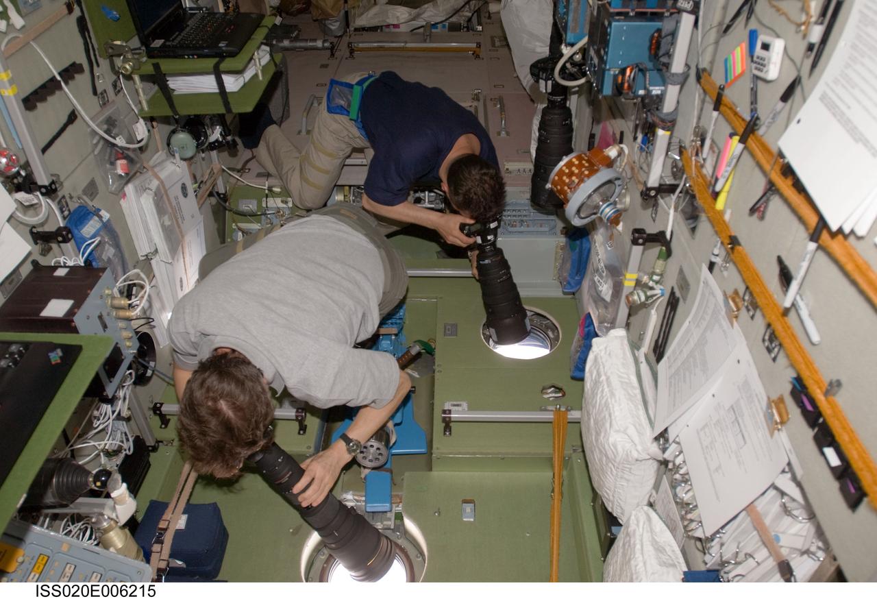 ISS020-E-006215 (1 June 2009) --- Cosmonaut Gennady Padalka (foreground), Expedition 20 commander; and cosmonaut Roman Romanenko, flight engineer, use still cameras at windows in the Zvezda Service Module of the International Space Station.