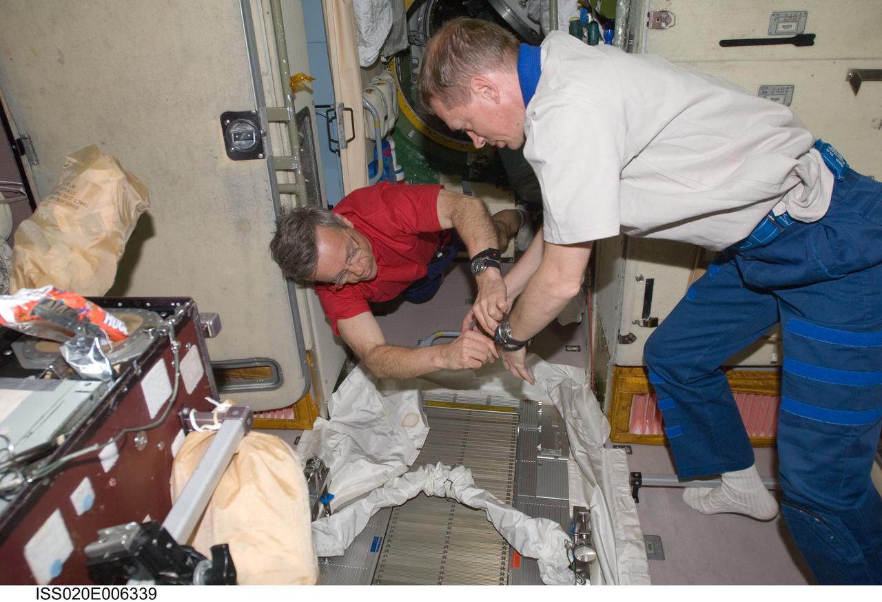 ISS020-E-006339 (3 June 2009) --- Canadian Space Agency astronaut Robert Thirsk (left) and European Space Agency astronaut Frank De Winne, both Expedition 20 flight engineers, perform in-flight maintenance on the Treadmill Vibration Isolation System (TVIS) in the Zvezda Service Module of the International Space Station.