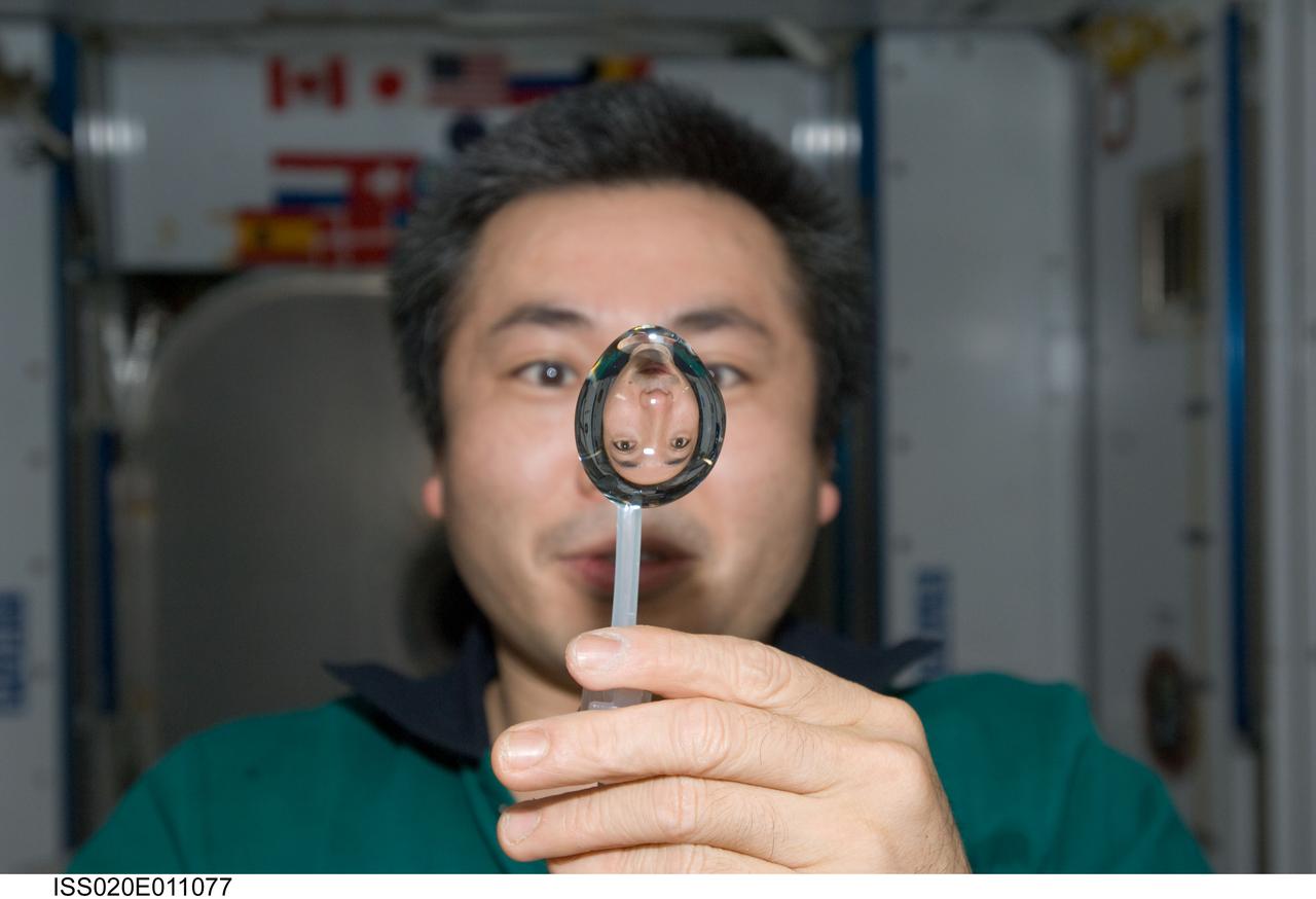ISS020-E-011077 (16 June 2009) --- Japan Aerospace Exploration Agency (JAXA) astronaut Koichi Wakata, Expedition 20 flight engineer, squeezes a water bubble out of his beverage container, showing his image refracted, in the Harmony node of the International Space Station.