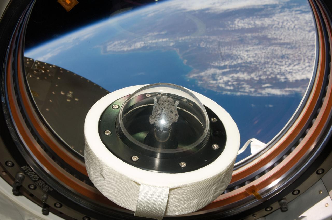 ISS020-E-14200 (FOR RELEASE 21 JULY 2009) --- A moon rock brought to Earth by Apollo 11, humans? first landing on the moon in July 1969, is shown as it floats aboard the International Space Station. Part of Earth can be seen through the window. The 3.6 billion year-old lunar sample was flown to the station aboard Space Shuttle mission STS-119 in April 2009 in honor of the July 2009 40th anniversary of the historic first moon landing. The rock, lunar sample 10072, was flown to the station to serve as a symbol of the nation?s resolve to continue the exploration of space. It will be returned on shuttle mission STS-128 to be publicly displayed.