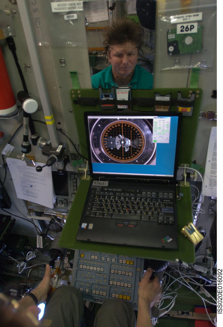 ISS020-E-016092 (1 July 2009) --- Cosmonaut Gennady Padalka (partially visible in the reflection of a mirror), Expedition 20 commander, uses an onboard laptop-based simulator in the Zvezda Service Module of the International Space Station to prepare for the relocation of the Soyuz TMA-14 spacecraft from Zvezda?s aft port to the Pirs Docking Compartment on July 2, 2009.