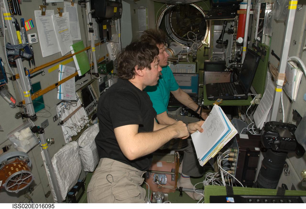 ISS020-E-016095 (1 July 2009) --- Cosmonaut Gennady Padalka (background), Expedition 20 commander; and NASA astronaut Michael Barratt, flight engineer, use an onboard laptop-based simulator in the Zvezda Service Module of the International Space Station to prepare for the relocation of the Soyuz TMA-14 spacecraft from Zvezda?s aft port to the Pirs Docking Compartment. Padalka and Barratt, along with Japan Aerospace Exploration Agency (JAXA) astronaut Koichi Wakata (out of frame), flight engineer, undocked the Soyuz spacecraft at 4:26 p.m. (CDT) and docked to the Pirs Docking Compartment at 4:54 p.m. on July 2, 2009.
