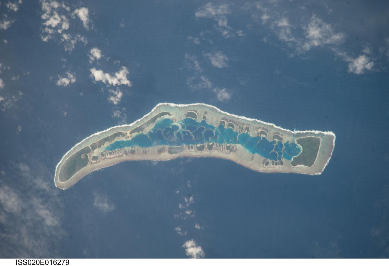 ISS020-E-016279 (1 July 2009) --- Millennium Island is featured in this image photographed by an Expedition 20 crew member on the International Space Station. Millennium Island ? known as Caroline Island prior to 2000 ? is located at the southern end of the Line Islands in the South Pacific Ocean. This uninhabited island is part of the Republic of Kiribati, an island nation comprised of 32 atolls (including Millennium Island) and one raised coral island. Millennium Island is formed from a number of smaller islets built on coral reefs. The coral reefs grew around a now-submerged volcanic peak, leaving a ring of coral around an inner lagoon. The islands above the waterline are composed primarily of limestone rock and sand derived from the reefs. At a maximum height of approximately 6 m above sea level, Millennium Island has been identified as being at great risk from sea level rise by the United Nations. The islets of Millennium Island are readily visible in this photograph as irregular green vegetated areas surrounding the inner lagoon. The shallow lagoon waters are a lighter blue than the deeper surrounding ocean water; tan linear ?fingers? within the lagoon are the tops of corals. The two largest islets are Nake Islet and South Islet, located at the north and south ends of Millennium Island respectively. The ecosystem of Millennium Island is considered to be relatively pristine despite periods of human habitation, guano mining, and agricultural activities, and the island has been recommended as both a World Heritage site and Biosphere Reserve.