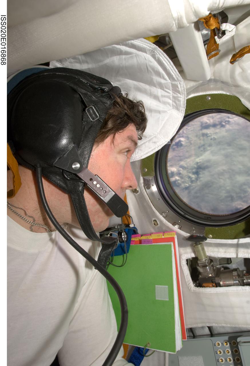 ISS020-E-016868 (2 July 2009) --- NASA astronaut Michael Barratt, Expedition 20 flight engineer, looks through a window on the Soyuz TMA-14 spacecraft during preparations for the relocation of the Soyuz from the Zvezda Service Module’s aft port to the Pirs Docking Compartment of the International Space Station.