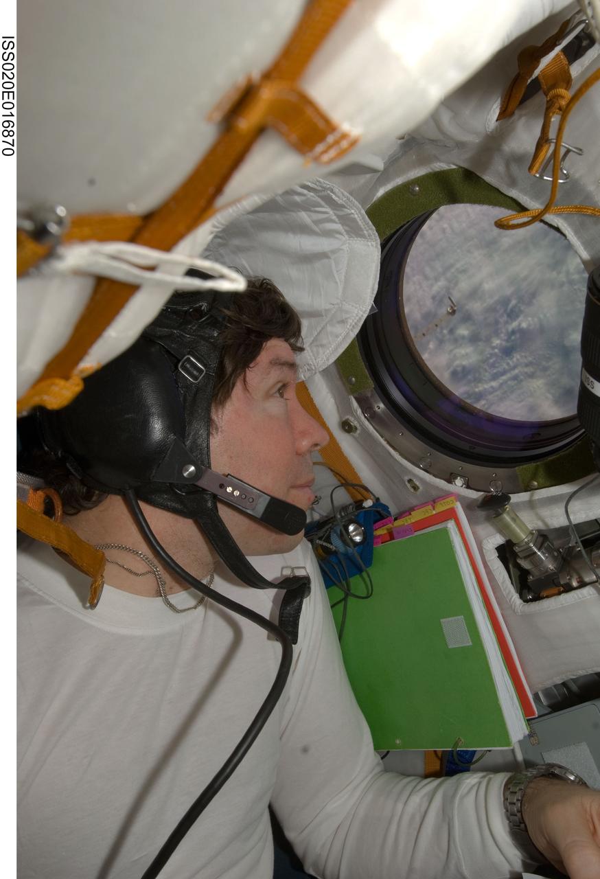 ISS020-E-016870 (2 July 2009) --- NASA astronaut Michael Barratt, Expedition 20 flight engineer, looks through a window on the Soyuz TMA-14 spacecraft during preparations for the relocation of the Soyuz from the Zvezda Service Module’s aft port to the Pirs Docking Compartment of the International Space Station.