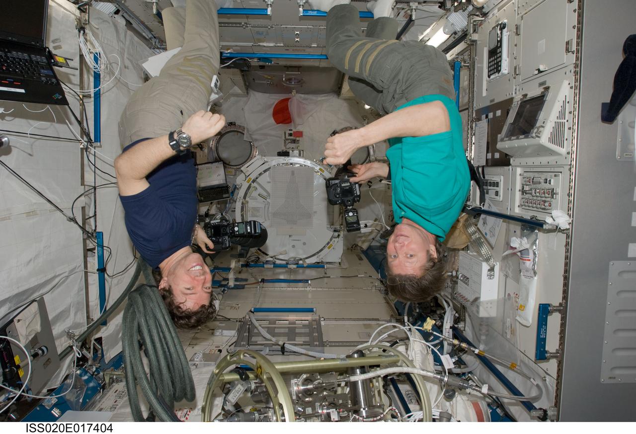 ISS020-E-017404 (6 July 2009) --- Cosmonaut Gennady Padalka (right), Expedition 20 commander; and NASA astronaut Michael Barratt, flight engineer, appear to be hanging upside down as they use still cameras in the Kibo laboratory of the International Space Station.