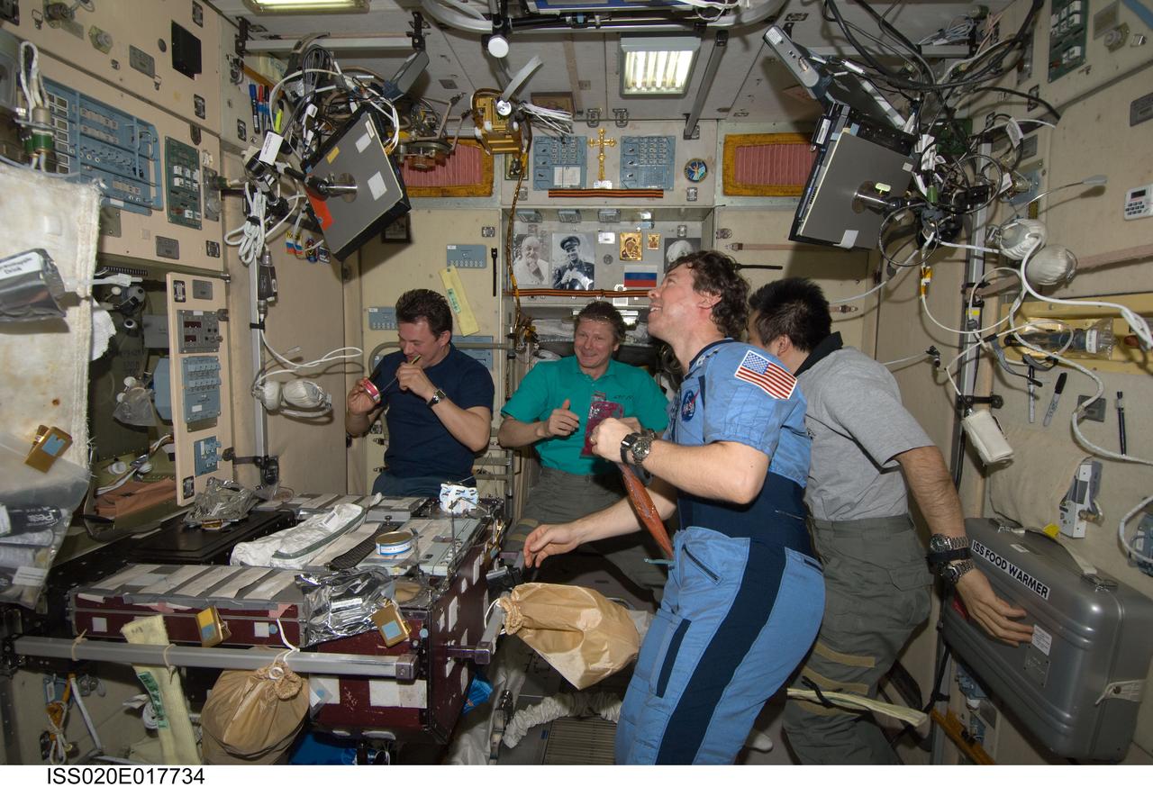 ISS020-E-017734 (4 July 2009) --- Expedition 20 crew members share a meal at the galley in the Zvezda Service Module of the International Space Station. Pictured (from the left) are cosmonauts Roman Romanenko, flight engineer, and Gennady Padalka, commander; along with Japan Aerospace Exploration Agency (JAXA) astronaut Koichi Wakata and NASA astronaut Michael Barratt, both flight engineers.