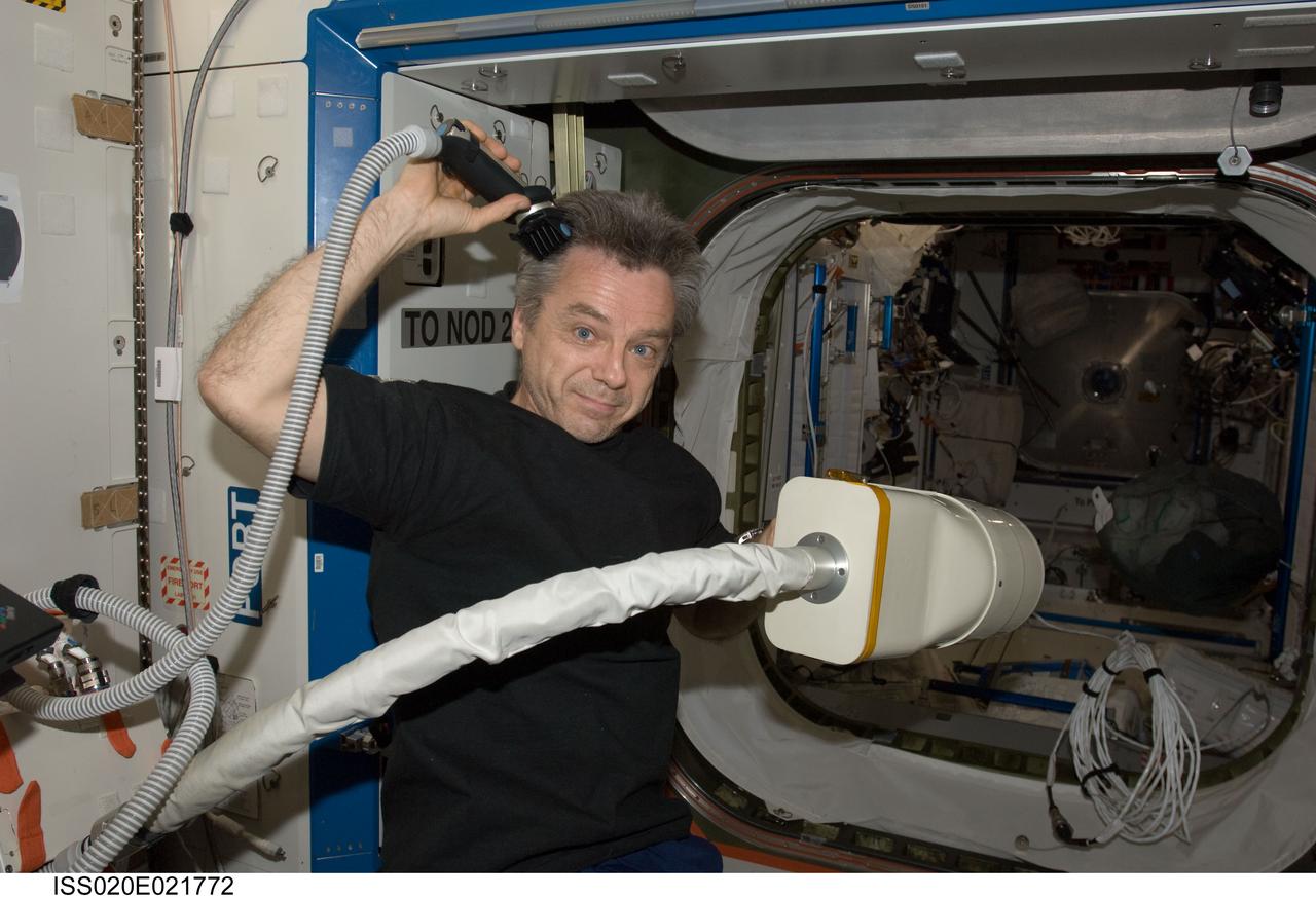 ISS020-E-021772 (17 July 2009) --- Canadian Space Agency astronaut Robert Thirsk, Expedition 20/21 flight engineer, gives himself a haircut and uses a vacuum cleaner to collect floating hairs. Company is en route to the International Space Station, as the six Expedition 20 inhabitants are preparing for seven crewmembers of STS-127 to come aboard on this flight day three.