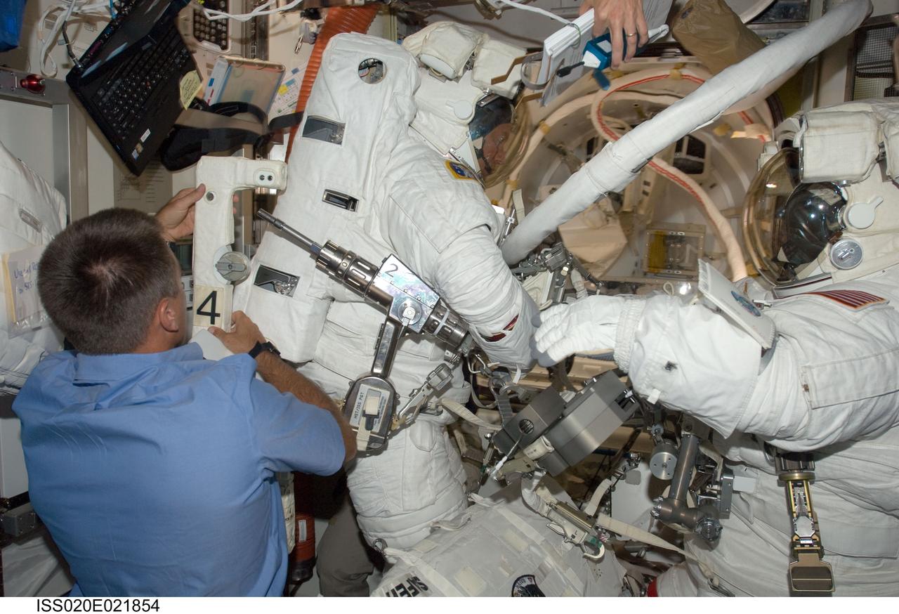 ISS020-E-021854 (18 July 2009) --- Astronauts Dave Wolf (right) and Tim Kopra (center) are suited and just about ready to exit the International Space Station's Quest airlock to begin the first of five scheduled spacewalks over the next several days. Astronaut Christopher Cassidy, foreground, assists Kopra with his backpack. When Wolf, Cassidy and five other astronauts return to Earth in the Space Shuttle Endeavour, Kopra will stay behind to serve a tour of duty on the orbital outpost.