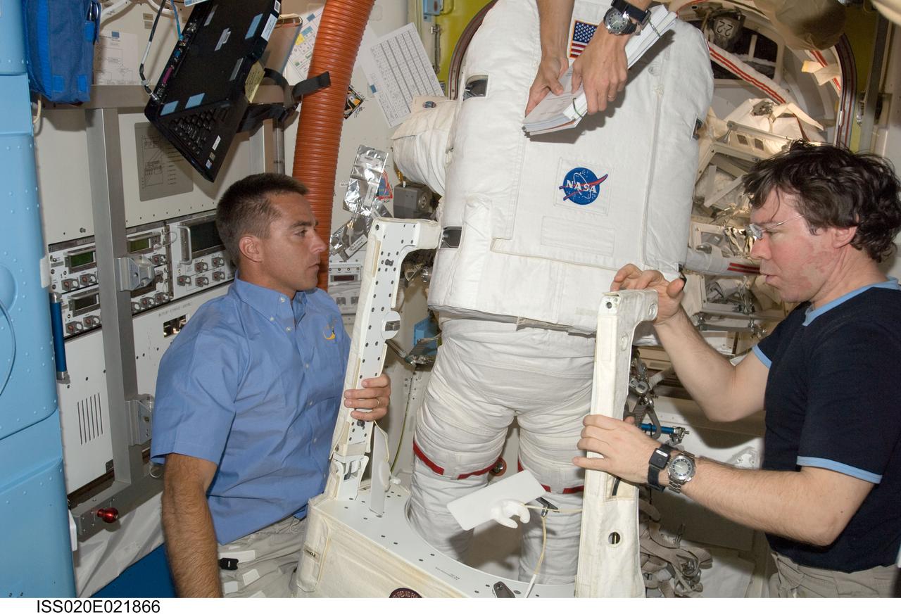 ISS020-E-021866 (18 July 2009) --- Astronauts Dave Wolf (in spacesuit with back to camera) and Tim Kopra (out of frame) are suited and just about ready to exit the International Space Station's Quest airlock to begin the first of five scheduled spacewalks over the next several days. The space walkers are assisted here by astronauts Christopher Cassidy (left), STS-127 mission specialist, and Mike Barratt, Expedition 20 flight engineer.