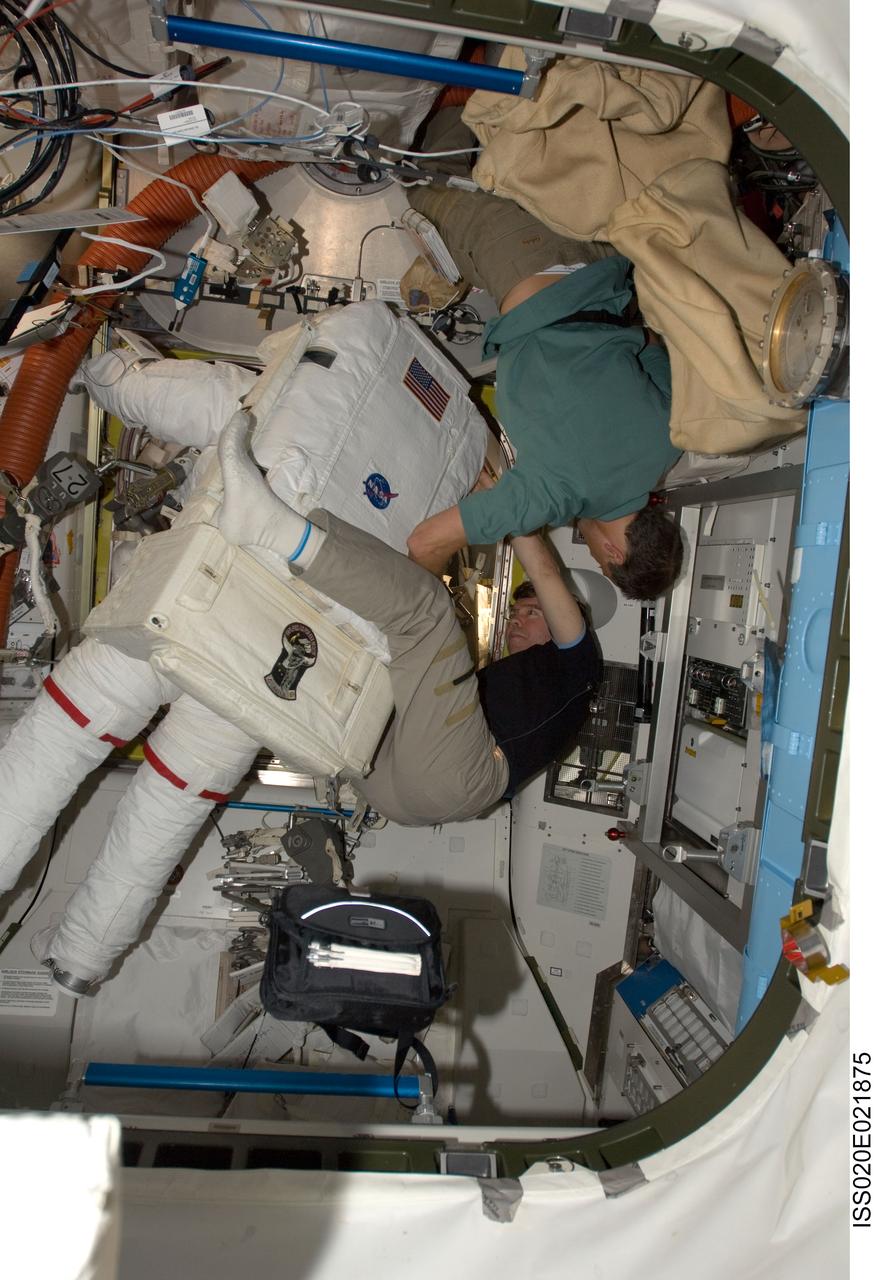 ISS020-E-021875 (18 July 2009) --- Astronaut Dave Wolf (back to camera) calls on a crewmember from the Space Shuttle Endeavour and another from the International Space Station's current crew to complete final touches on his space suit. Astronaut Mike Barratt, Expedition 20 flight engineer, is at frame bottom, and astronaut Christopher Cassidy, STS-127 mission specialist, is near the top. Wolf was about to participate in the first of five overall sessions of extravehicular activity scheduled over the next several days.