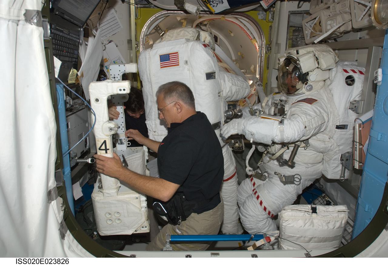 ISS020-E-023826 (24 July 2009) --- Astronaut Dave Wolf assists astronaut Tom Marshburn with some final touches on his extravehicular mobility unit spacesuit in the joint airlock, while astronaut Christopher Cassidy stands suited and almost ready at right. Marshburn and Cassidy were about to participate in the July 24 flight day 10 spacewalk. They are scheduled to wrap up the EVA work with a fifth overall session on July 27. The three mission specialists are part of a 13-member aggregation of astronauts and cosmonauts currently onboard the orbital outpost while its crew of six plays host to Endeavour's crew of seven.