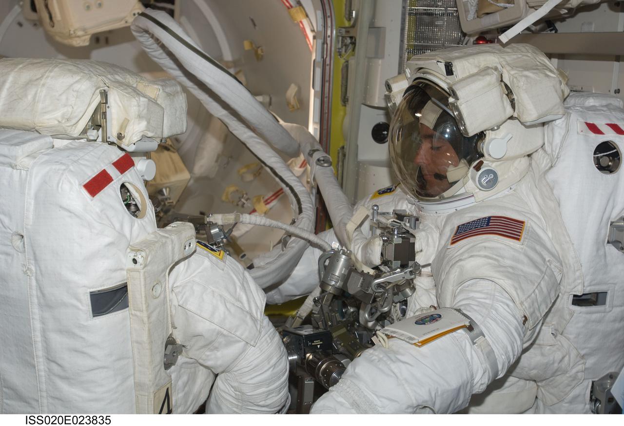 ISS020-E-023835 (24 July 2009) --- Astronauts Tom Marshburn (left) and Christopher Cassidy stand suited and almost ready to participate in the July 24 flight day 10 spacewalk. The two are scheduled to wrap up the EVA work with a fifth overall session on July 27. The mission specialists are part of a 13-member aggregation of astronauts and cosmonauts currently onboard the orbital outpost while its crew of six plays host to Endeavour's crew of seven.