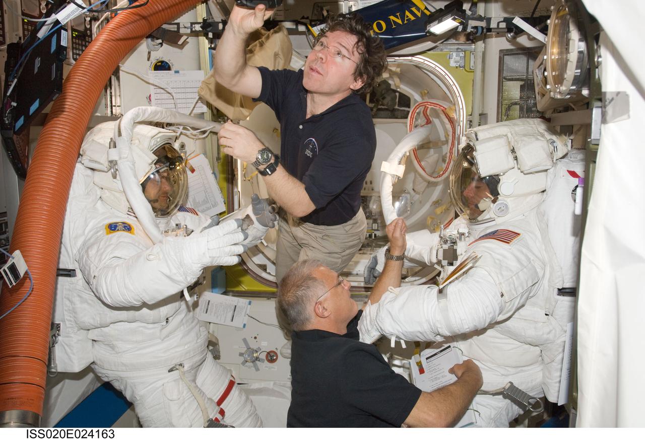 ISS020-E-024163 (24 July 2009) --- Astronauts Mike Barratt (top center), Expedition 20 flight engineer, and Dave Wolf (bottom center), STS-127 mission specialist, assist astronaut Tom Marshburn (left) and Christopher Cassidy following the completion of the fourth spacewalk for the joint shuttle-station crews currently aboard the International Space Station while it is docked to the Space Shuttle Endeavour.