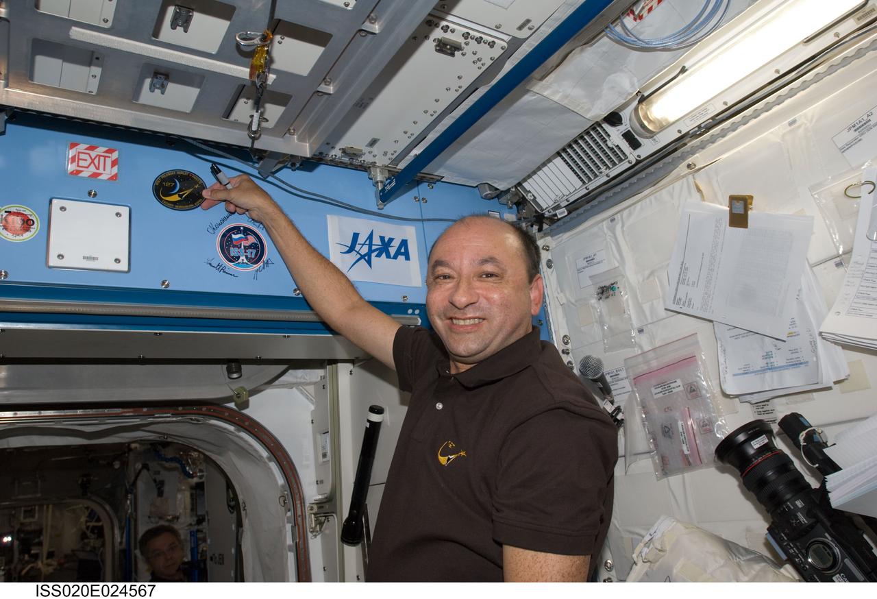 ISS020-E-024567 (25 July 2009) --- Astronaut Mark Polansky, STS-127 commander, places the STS-127 patch above a hatch in the Kibo laboratory, which adds to the growing collection of insignias representing crews who have lived and worked on the International Space Station.