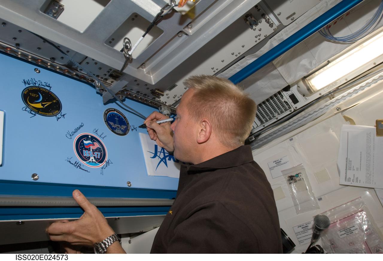 ISS020-E-024573 (25 July 2009) --- Astronaut Tim Kopra, Expedition 20 flight engineer, signs the Expedition 20 patch in the Kibo laboratory, which was added to the growing collection of insignias representing crews who have lived and worked on the International Space Station.