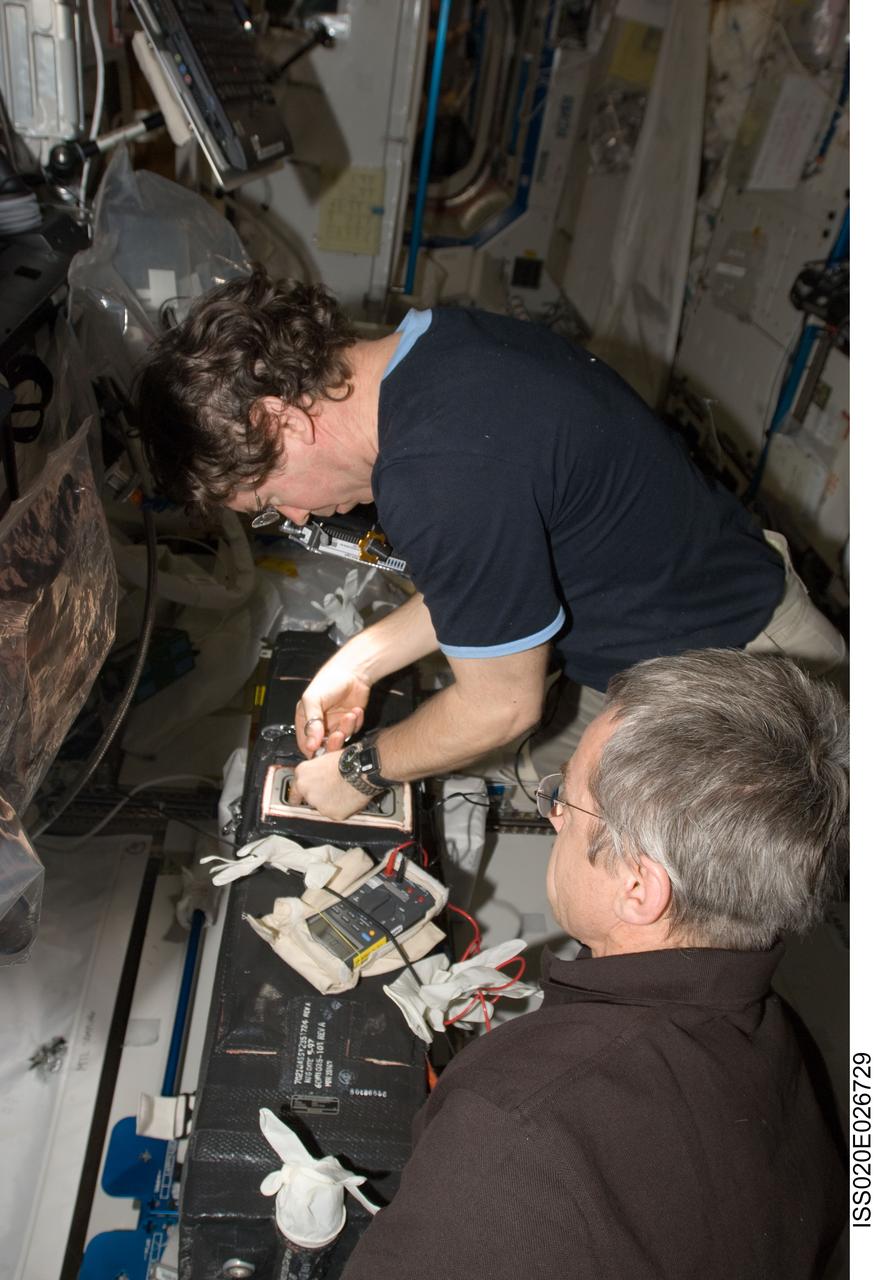 ISS020-E-026729 (31 July 2009) --- NASA astronaut Michael Barratt and Canadian Space Agency astronaut Robert Thirsk (foreground), both Expedition 20 flight engineers, work with the Carbon Dioxide Removal Assembly (CDRA) wire cutting and safing procedures to eliminate shorted heated wires in the Destiny laboratory of the International Space Station.