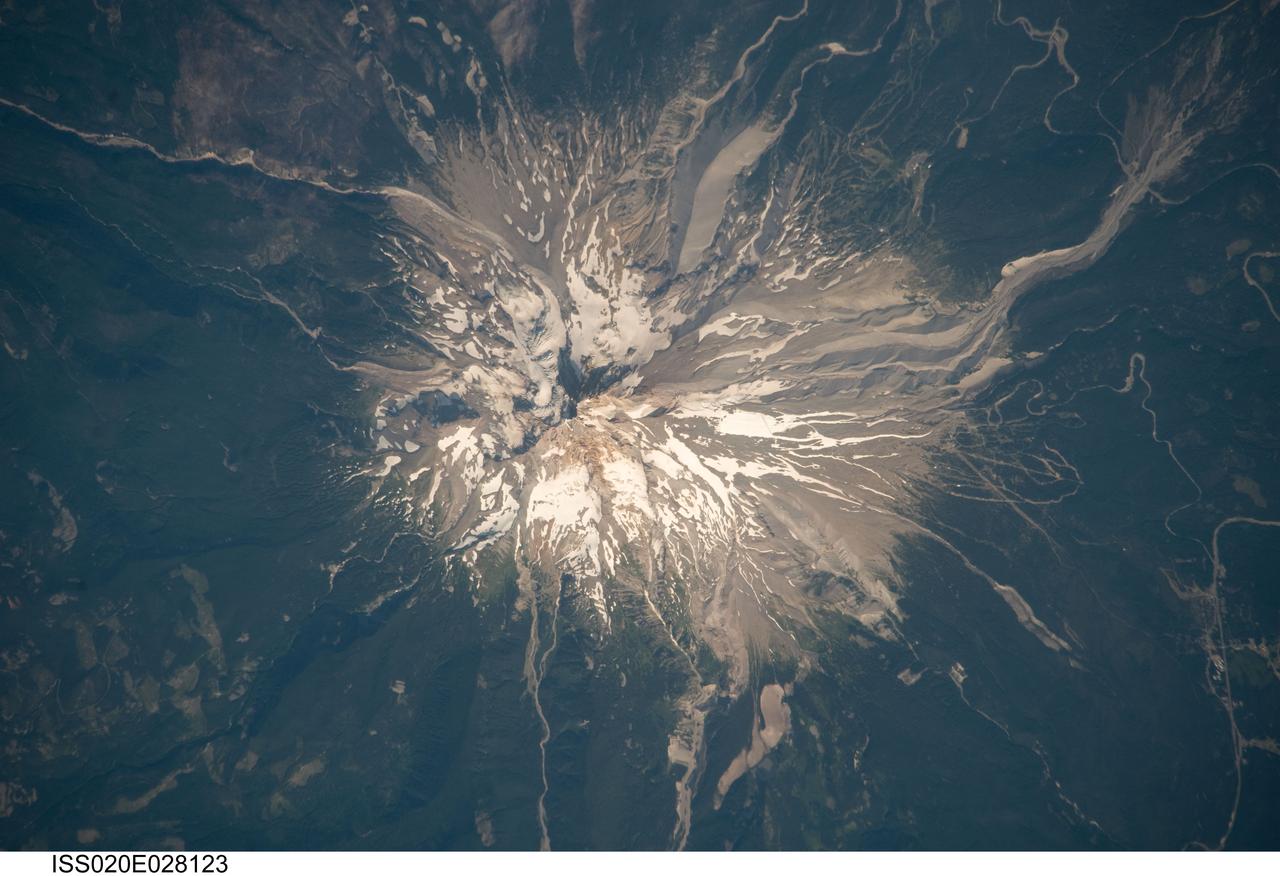 ISS020-E-028123 (5 Aug. 2009) --- Mount Hood, Oregon is featured in this image photographed by an Expedition 20 crew member on the International Space Station. Mount Hood is located within the Cascade Range of the western United States, and is the highest peak (3,426 m) in Oregon. The Cascade Range is characterized by a line of volcanoes associated with a slab of oceanic crust that is subducting, or descending underneath, the westward moving continental crust of North America.  Magma generated by the subduction process rises upward through the crust and feeds a line of active volcanoes that extends from northern California in the United States to southern British Columbia in Canada. While hot springs and steam vents are still active on Mount Hood, the last eruption from the volcano occurred in 1866. The volcano is considered dormant, but still actively monitored. Separate phases of eruptive activity produced pyroclastic flows and lahars ? mudflows ? that carried erupted materials down all of the major rivers draining the volcano. Gray volcanic deposits extend southwards along the banks of the White River (upper right), and form several prominent ridges along the southeast to southwest flanks of the volcano. The deposits contrast sharply with the green vegetated lower flanks of the volcano. The Mount Hood stratovolcano ? a typically cone-shaped volcanic structure formed by interlayered lava flows and explosive eruption deposits ? hosts twelve mapped glaciers along its upper flanks (center). Like other glaciers in the Pacific Northwest, the Hood glaciers have been receding due to global warming, and have lost an estimated 61 percent of their volume over the past century. The predicted loss of glacial meltwater under future warming scenarios will have significant effects on regional hydrology and water supplies.