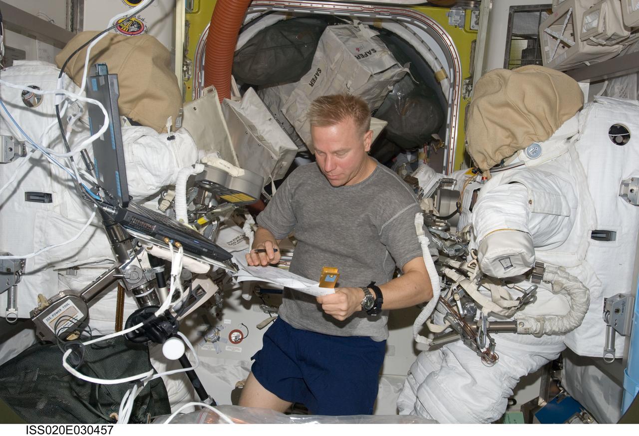 ISS020-E-030457 (13 Aug. 2009) --- Astronaut Tim Kopra, Expedition 20 flight engineer, looks over a checklist in the Quest airlock of the International Space Station.