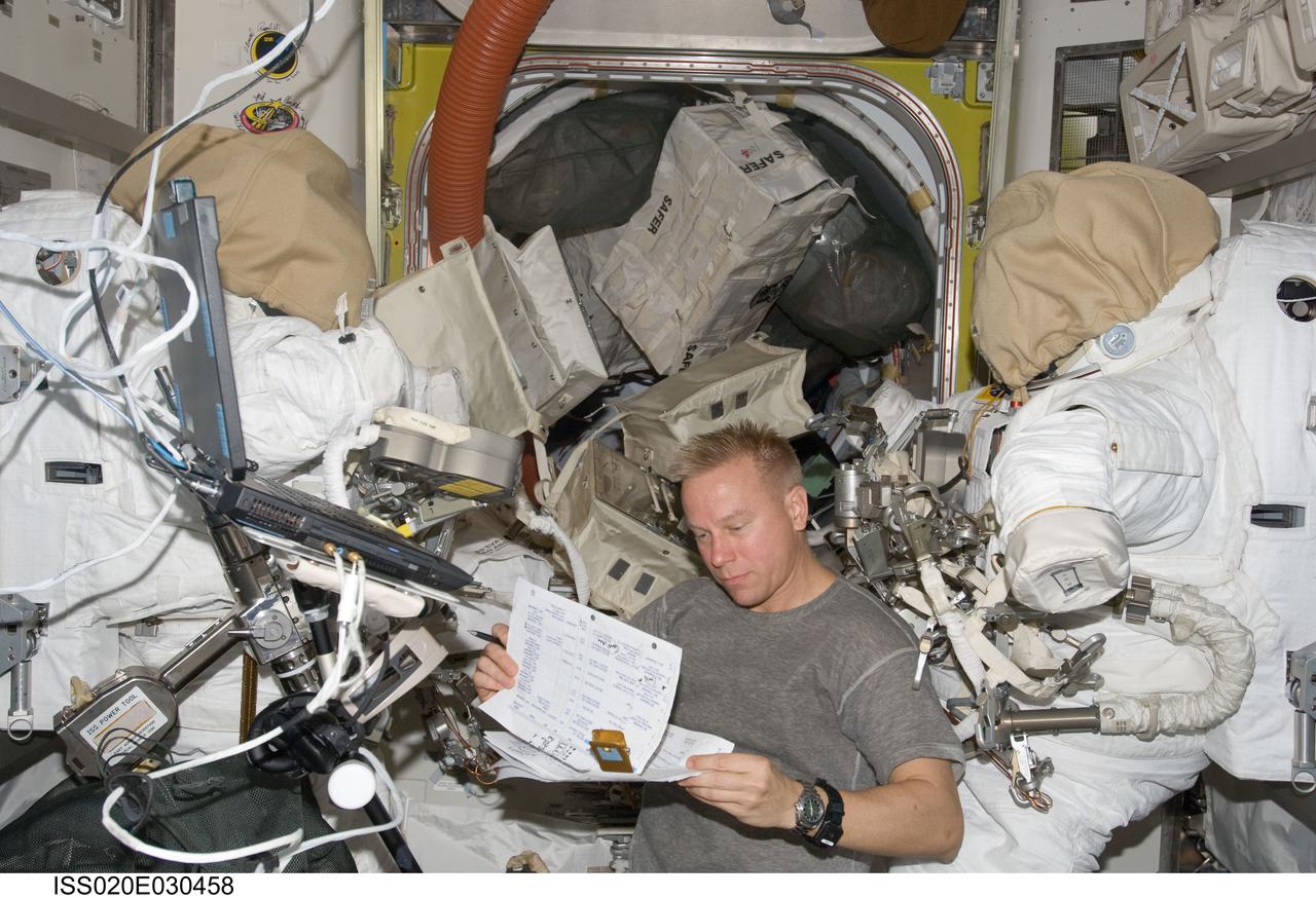 ISS020-E-030458 (13 Aug. 2009) --- Astronaut Tim Kopra, Expedition 20 flight engineer, looks over a checklist in the Quest airlock of the International Space Station.