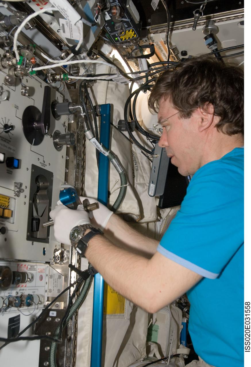 ISS020-E-031558 (18 Aug. 2009) --- NASA astronaut Michael Barratt, Expedition 20 flight engineer, conducts a Surface, Water and Air Biocharacterization (SWAB) water sampling from the Potable Water Dispenser (PWD) in the Destiny laboratory of the International Space Station. SWAB uses advanced molecular techniques to comprehensively evaluate microbes onboard the space station, including pathogens (organisms that may cause disease). This study will allow an assessment of the risk of microbes to the crew and the spacecraft.
