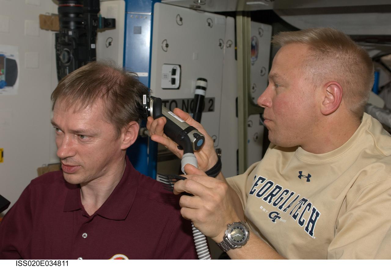 ISS020-E-034811 (9 Aug. 2009) --- NASA astronaut Tim Kopra, Expedition 20 flight engineer, trims European Space Agency astronaut Frank De Winne’s hair in the Destiny laboratory of the International Space Station. Kopra used hair clippers fashioned with a vacuum device to garner freshly cut hair.