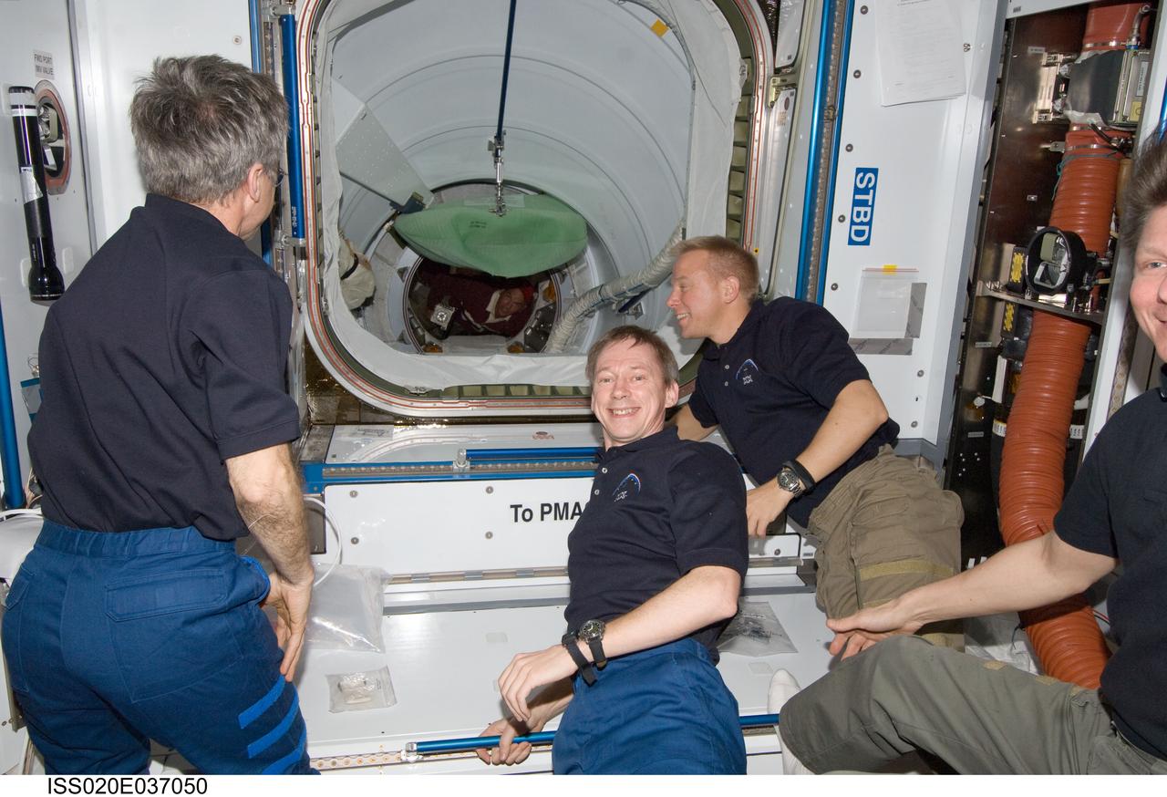 ISS020-E-037050 (30 Aug. 2009) --- Expedition 20 crew members are pictured in the Harmony node of the International Space Station as Space Shuttle Discovery’s crew ingress through the station’s Pressurized Mating Adapter 2 (PMA-2). Pictured (from the left) are Canadian Space Agency astronaut Robert Thirsk, European Space Agency astronaut Frank De Winne and NASA astronaut Tim Kopra, all flight engineers; along with Russian cosmonaut Gennady Padalka (partially out of frame at right), commander. Astronaut Rick Sturckow, STS-128 commander, is visible in the background as he leads his crew onto the space station.