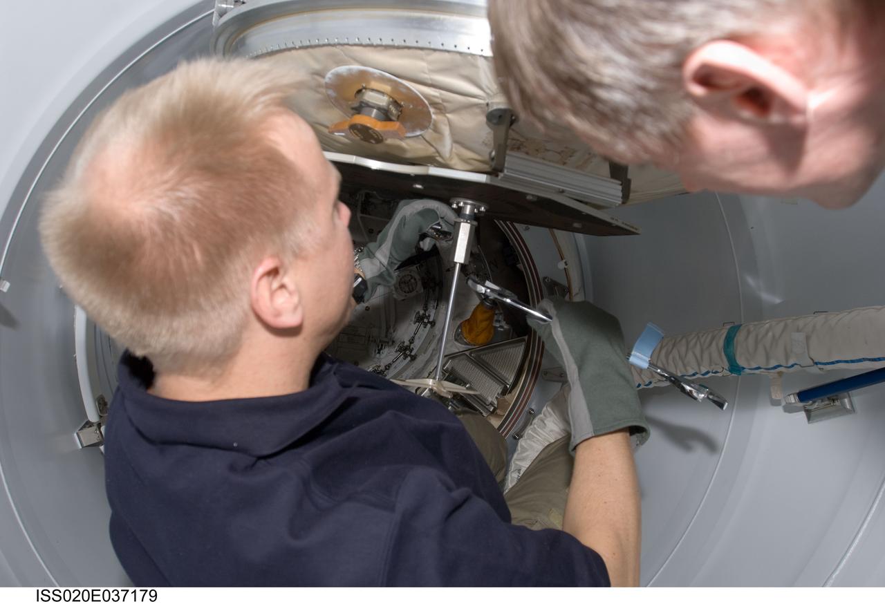 ISS020-E-037179 (30 Aug. 2009) --- NASA astronaut Tim Kopra (left) and European Space Agency astronaut Frank De Winne, both Expedition 20 flight engineers, work in the Pressurized Mating Adapter 2 (PMA-2) of the International Space Station while Space Shuttle Discovery (STS-128) remains docked with the station.
