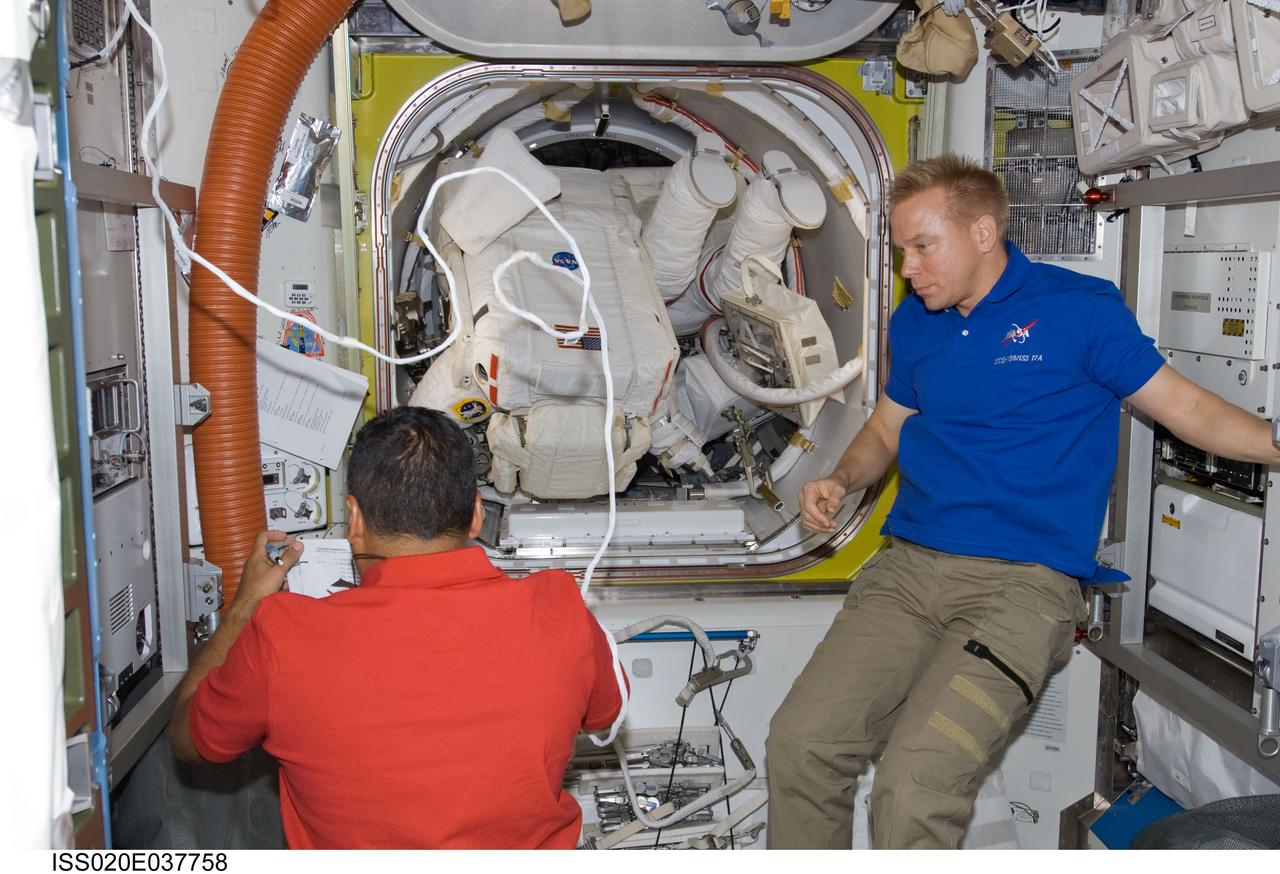 ISS020-E-037758 (1 Sept. 2009) --- Astronauts Jose Hernandez (left) and Tim Kopra, both STS-128 mission specialists, are pictured in the Quest airlock of the International Space Station as astronauts John “Danny” Olivas, mission specialist; and Nicole Stott, Expedition 20 flight engineer, prepare to exit the airlock to begin the mission’s first session of extravehicular activity.