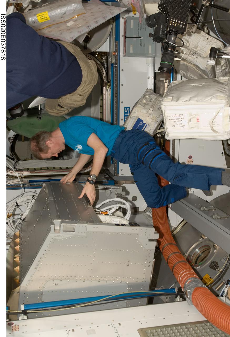 ISS020-E-037818 (2 Sept. 2009) --- European Space Agency astronaut Frank De Winne, Expedition 20 flight engineer, moves a rack through a hatch in the Harmony node of the International Space Station while Space Shuttle Discovery (STS-128) remains docked with the station.