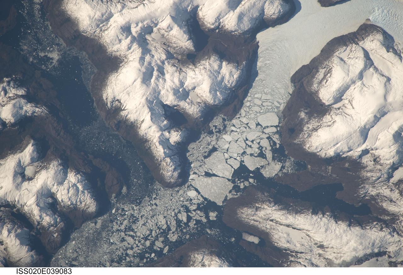 ISS020-E-039083 (6 Sept. 2009) --- Glacier outlet in the Southern Patagonian Ice Field of Chile is featured in this image photographed by an Expedition 20 crew member on the International Space Station. The Southern Patagonian Ice Field of Chile and Argentina hosts a spectacular array of glaciers and associated glacial features within the southern Andes Mountains. Glaciers flowing downhill on the eastern side of the mountains have outlets into several large freshwater lakes. On the western side of the mountains, glaciers release ice into the Pacific Ocean via an intricate network of fjords. Fjords are steep valleys originally cut by glaciers during periods of lower sea level that are now inundated. As glaciers flow into the fjord, ice at the front of the glacier begins to break off and form icebergs that can float out to sea ? a process known as calving. This detailed photograph shows the merged outlet of Penguin Glacier and HPS 19 into a fjord carved into the snow-covered mountains of the southern Andes. The designation HPS stands for Hielo Patagonico Sur (e.g. Southern Patagonian Ice field) and is used to identify glaciers that have no other geographic name. Ice flowing into the fjord begins to break up at center, forming numerous icebergs ? the largest visible in this image is approximately 2 kilometers in width. The large ice masses visible at center have a coarse granular appearance due to variable snow cover, and mixing and refreezing of ice fragments prior to floating free.
