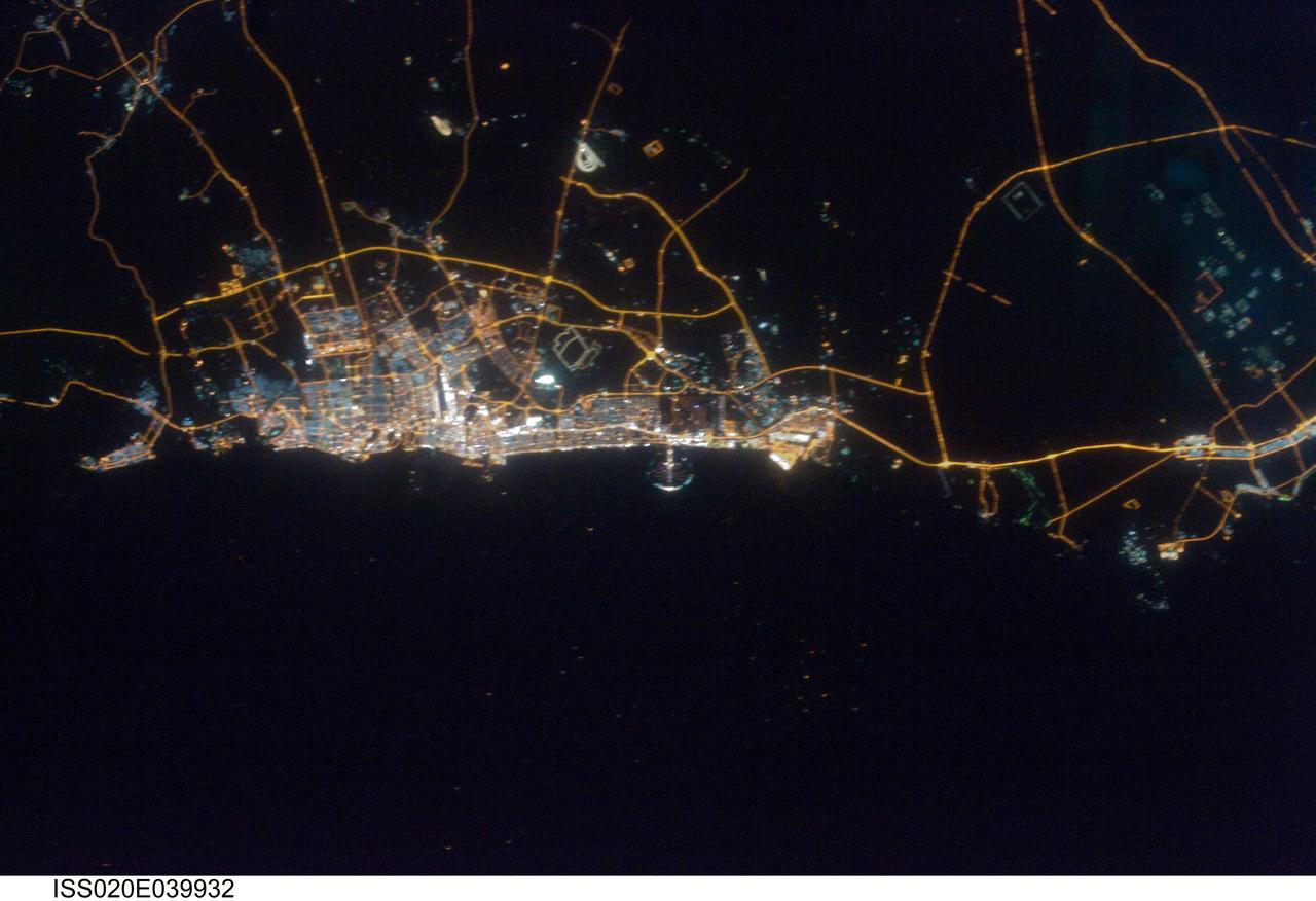 ISS020-E-039932 (11 Sept. 2009) --- City of Dubai, United Arab Emirates is featured in this night view photographed by an Expedition 20 crew member on the International Space Station. The city of Dubai is the largest metropolitan area in the emirate of Dubai, one of the member states of the United Arab Emirates. Dubai is located along the southern Persian Gulf on the Arabian Peninsula, and its signature city is known for high profile architectural and development projects. Among the most notable is the Palm Island Resort, a manmade peninsula and surrounding islands built from over 50 million cubic meters of sand. Two other island projects, one similar to the Palm Island Resort and another crafted to look like a map of the world, are also underway along the Dubai coastline. This night time photograph of the city of Dubai was taken at approximately 2:00 a.m. local time. Orange sodium vapor lights trace out the major highways and surface street grid in and around the metropolitan area, while grey-white mercury vapor lamps fill in the commercial and residential areas. The lighted islands and peninsula of the Palm Island Resort are clearly visible along the coastline. An interesting spiral pattern of lights on the southeastern fringe of the urban area is a camel racetrack. Night time images like these are useful to climate modelers, urban planners, and geographers as they allow for simple definition of urban (densely lit) and rural (sparely lit) areas.