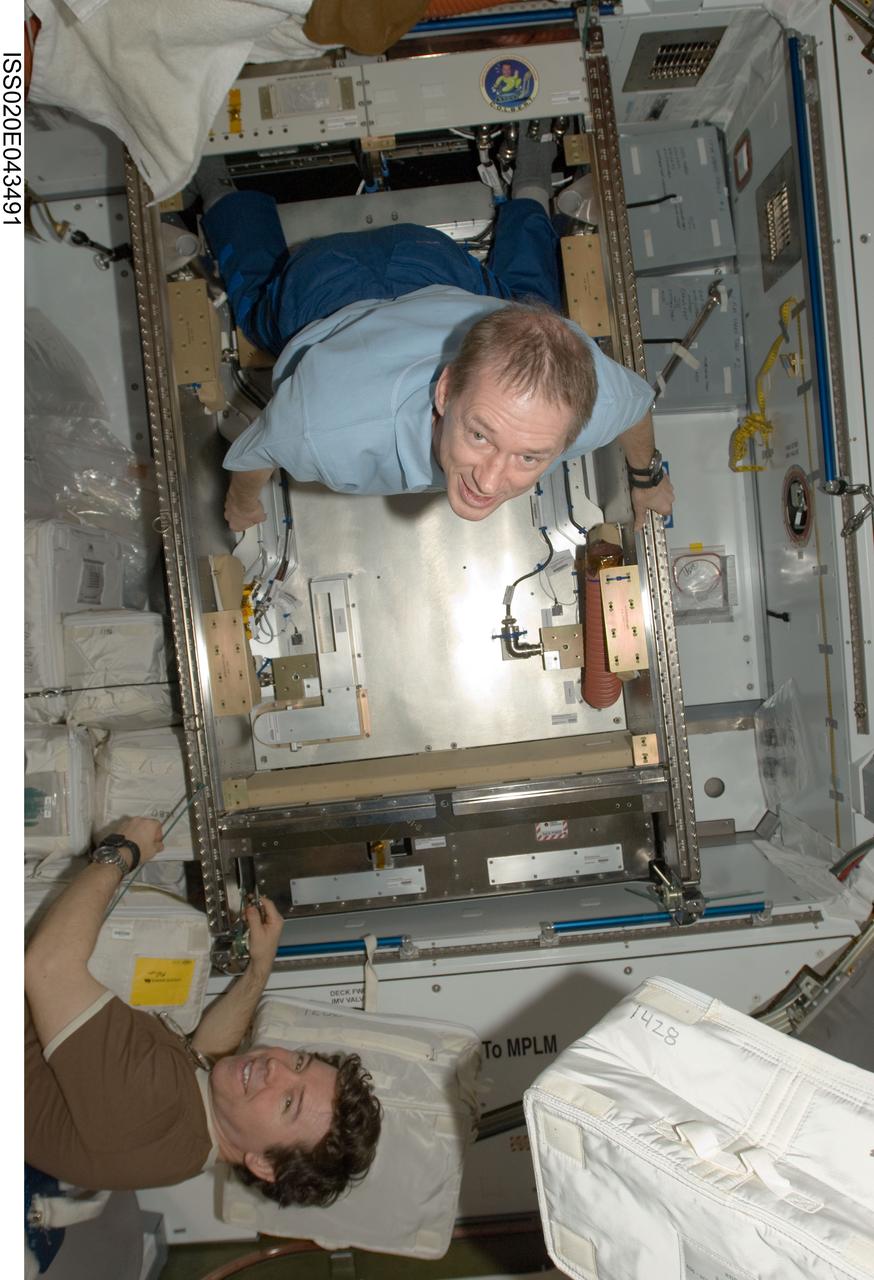 ISS020-E-043491 (29 Sept. 2009) --- Russian cosmonaut Roman Romanenko (bottom) and European Space Agency astronaut Frank De Winne, both Expedition 20 flight engineers, work in the Harmony node of the International Space Station.
