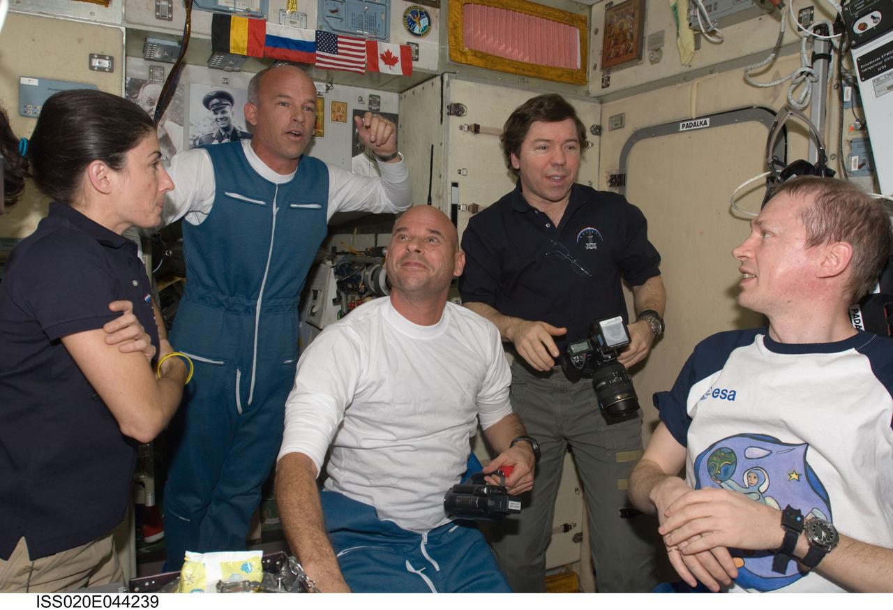 ISS020-E-044239 (2 Oct. 2009) --- NASA astronaut Jeffrey Williams (second left), Expedition 21 flight engineer; and spaceflight participant Guy Laliberte (center) are pictured in the Zvezda Service Module of the International Space Station, shortly after arriving onboard a Soyuz spacecraft along with Russian cosmonaut Maxim Suraev (out of frame), Expedition 21 flight engineer. Also pictured are NASA astronauts Nicole Stott and Michael Barratt (right background); along with European Space Agency astronaut Frank De Winne, all Expedition 20 flight engineers.