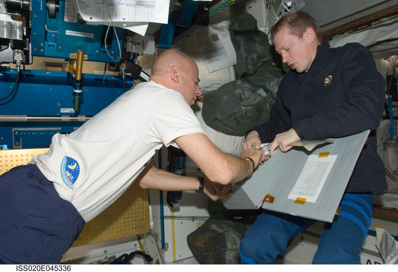 ISS020-E-045336 (5 Oct. 2009) --- European Space Agency astronaut Frank De Winne, Expedition 20 flight engineer and Expedition 21 commander; and spaceflight participant Guy Laliberte make food selections from a stowage container in the Unity node of the International Space Station.