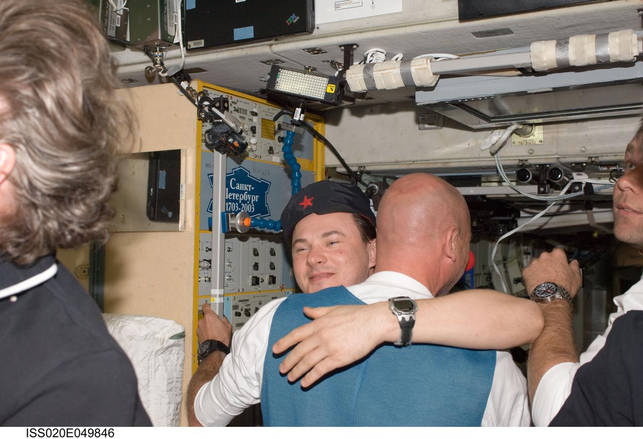 ISS020-E-049846 (2 Oct. 2009) --- In the International Space Station?s Zvezda Service Module, Russian cosmonaut Roman Romanenko, Expedition 20/21 flight engineer, welcomes spaceflight participant Guy Laliberte (back to camera) after arriving onboard a Soyuz spacecraft with NASA astronaut Jeffrey Williams (out of frame), Expedition 21 flight engineer and Expedition 22 commander; and Russian cosmonaut Maxim Suraev (mostly out of frame at right), Expedition 21/22 flight engineer.