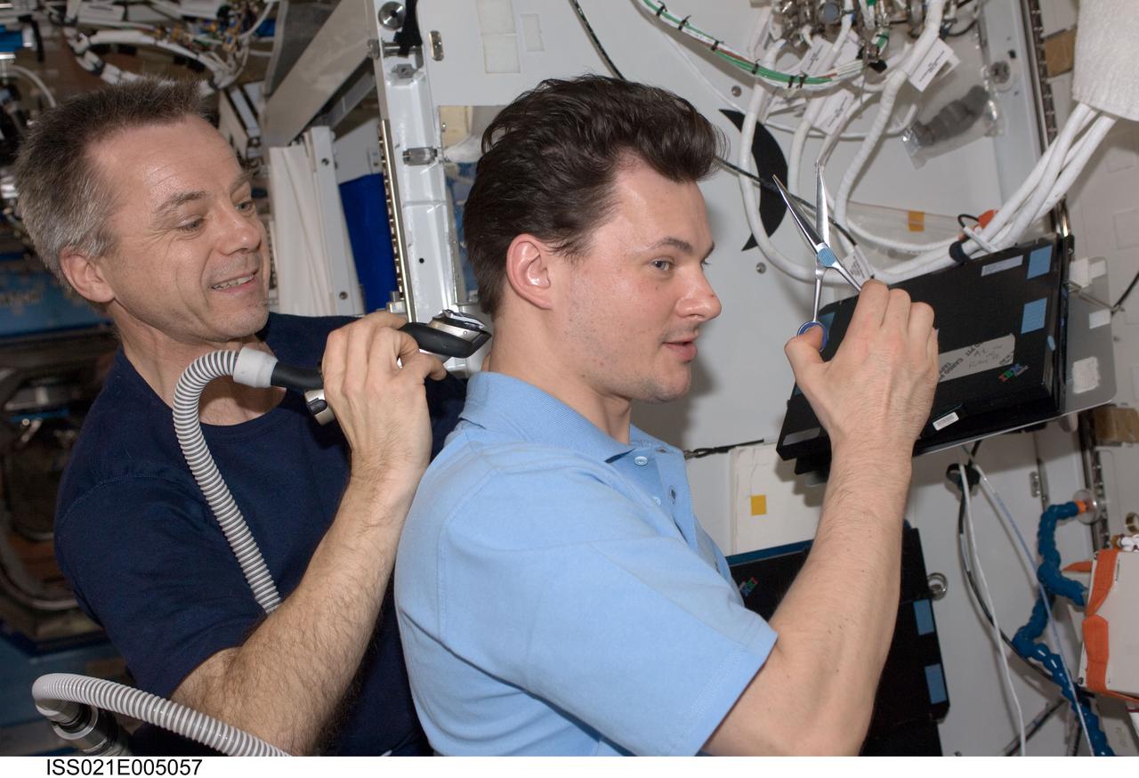 ISS021-E-005057 (11 Oct. 2009) --- Canadian Space Agency astronaut Robert Thirsk, Expedition 21 flight engineer, trims Russian cosmonaut Roman Romanenko's hair in the Destiny laboratory of the International Space Station. Thirsk used hair clippers fashioned with a vacuum device to garner freshly cut hair.