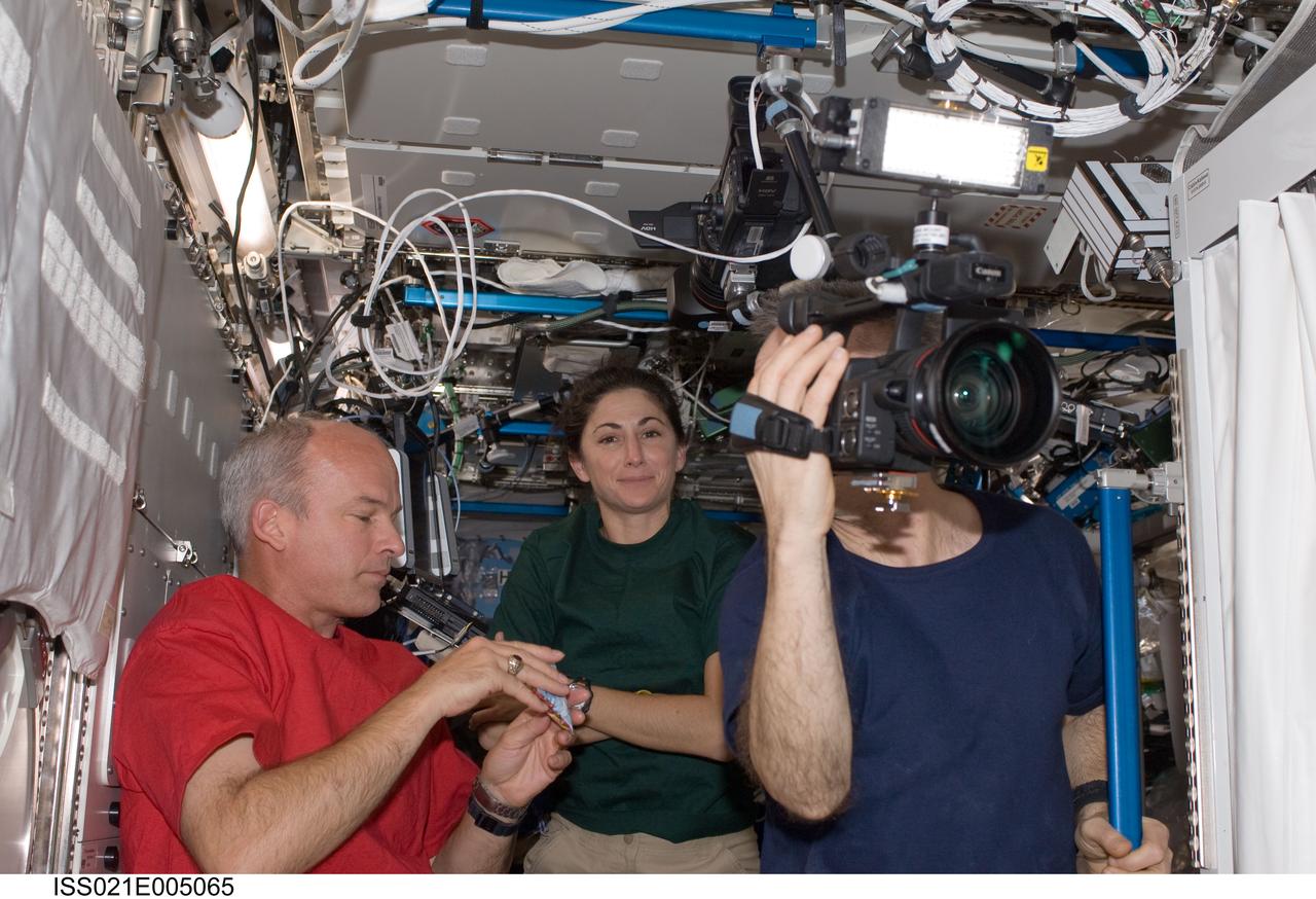 ISS021-E-005065 (11 Oct. 2009) --- Canadian Space Agency astronaut Robert Thirsk, Expedition 21 flight engineer, uses a High Definition Video (HDV) camera in the Destiny laboratory of the International Space Station. NASA astronauts Jeffrey Williams and Nicole Stott, both Expedition 21 flight engineers, are also pictured.